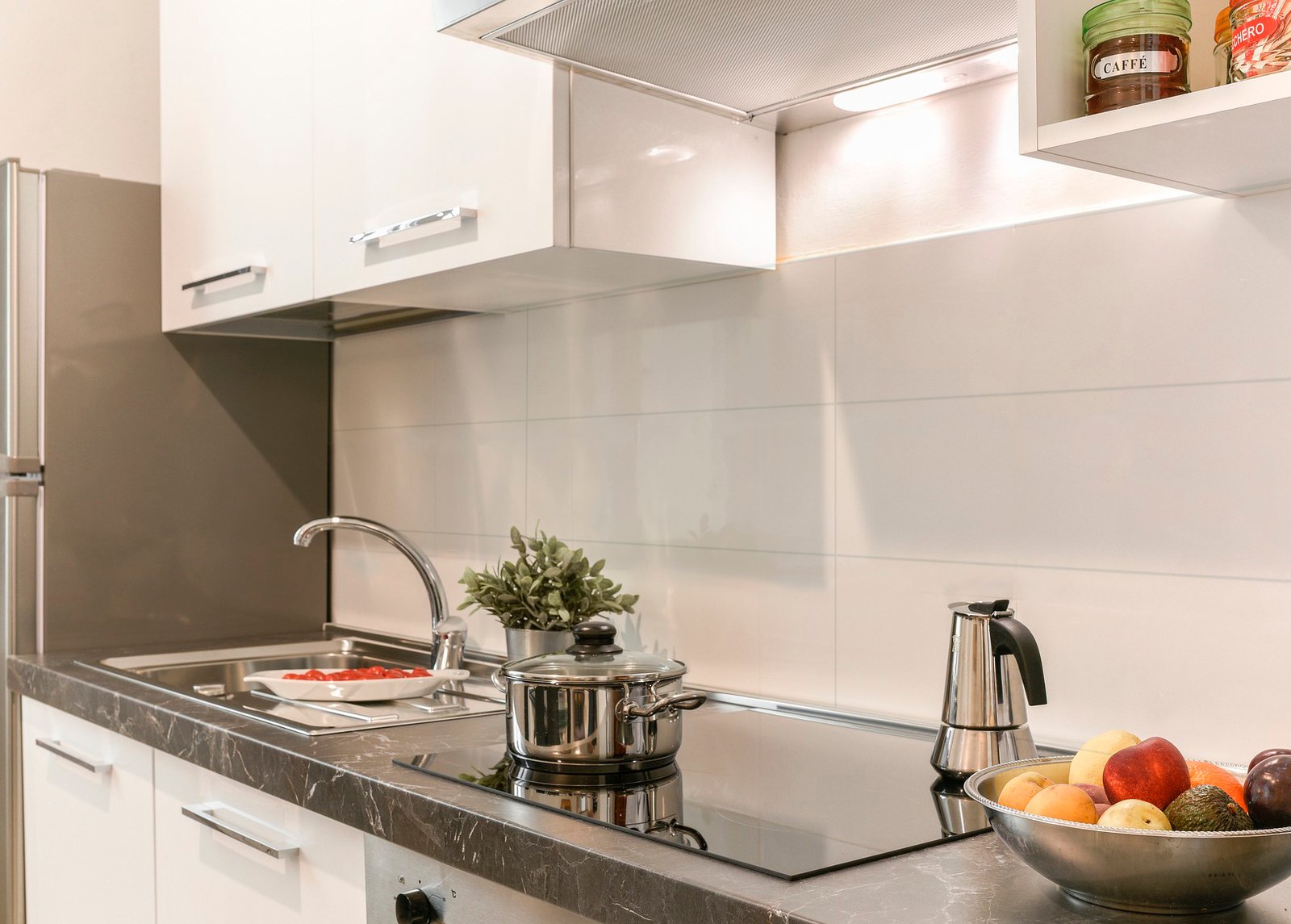 Cozinha moderna branca com bancada de pedra preta e eletrodomésticos embutidos — projeto 20x80, por Cerámica Alberdi