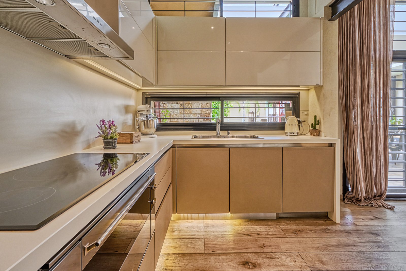 Cocina moderna con muebles beige, encimera de mármol, ventana amplia y suelo de madera — proyecto Remodelacion cocina y playroom, por Paula Accarino, en Paraná 120