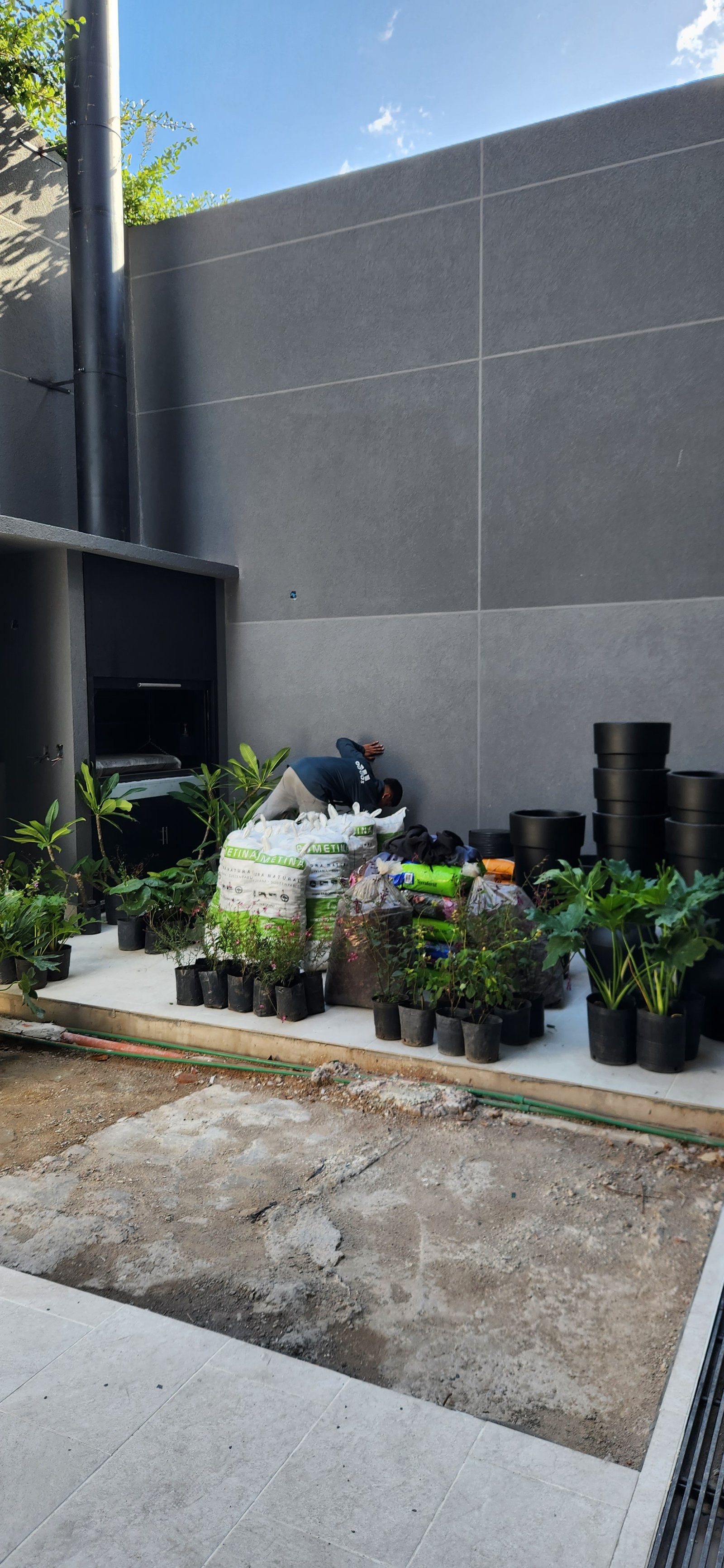 Patio en construcción con plantas y materiales de jardinería — proyecto Casa ENRICH, por Estudio Rifahi, en Colegiales