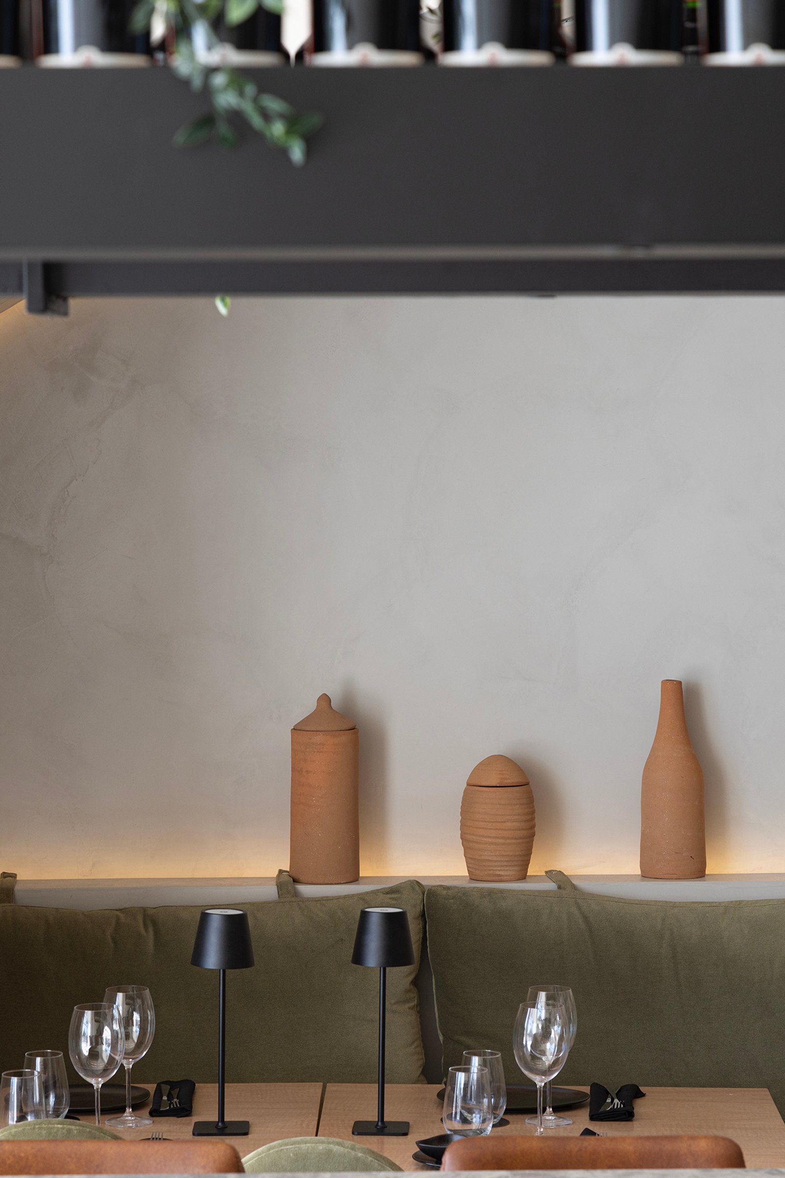 Comedor moderno con banco verde, lámparas de mesa y objetos de terracota — proyecto HATSU Núñez - MZV Arquitectura, por Gaby Alfonso, en Buenos Aires