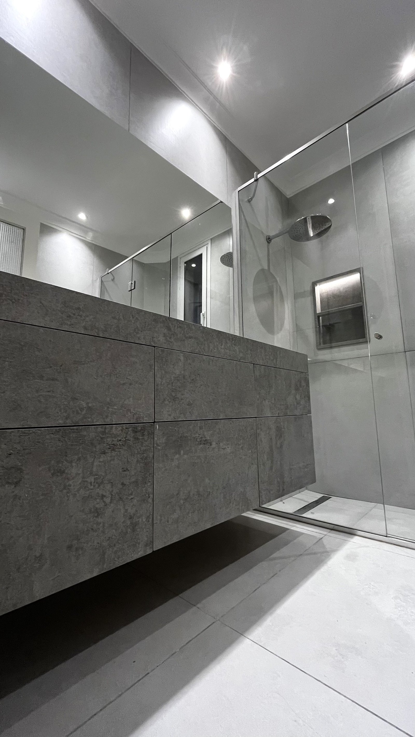 Baño moderno con mueble de piedra gris, ducha de cristal y luz indirecta — proyecto CASA CERRITO (German Salas arquitectura), por German Salas arquitectura - San Isidro, en Buenos 