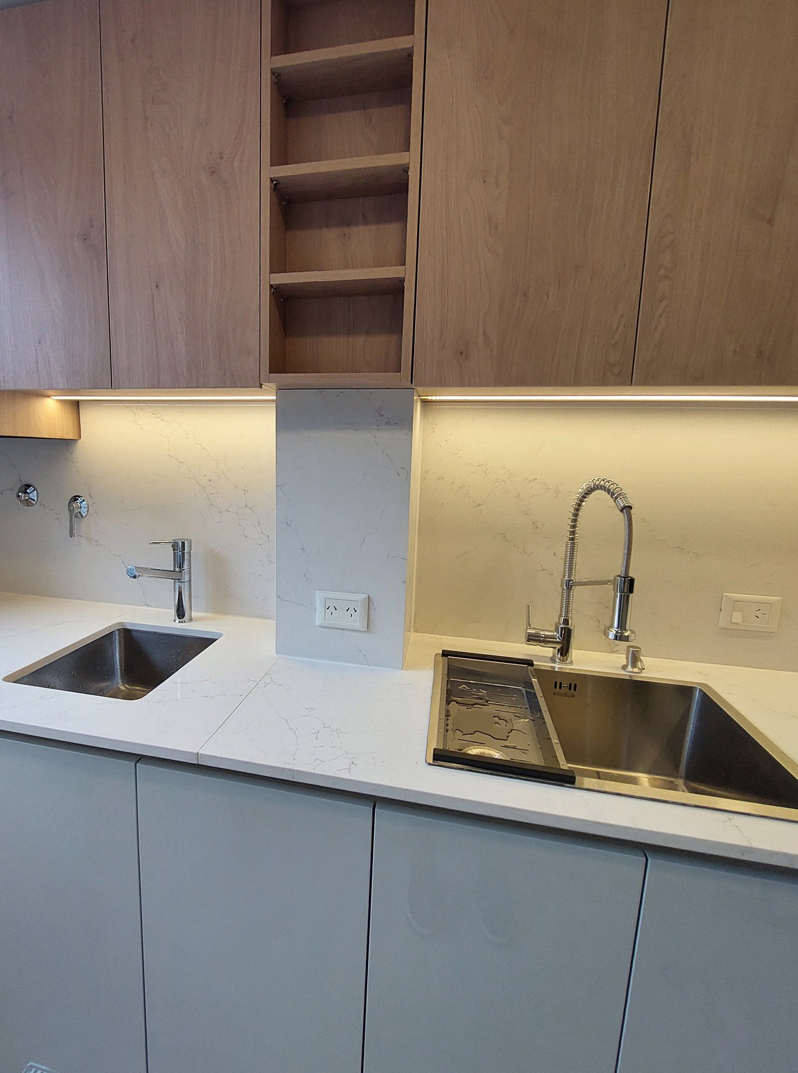 Cozinha moderna com armários de madeira natural e bancadas de pedra branca — projeto LBT, por Arquitecta, em La Lucila