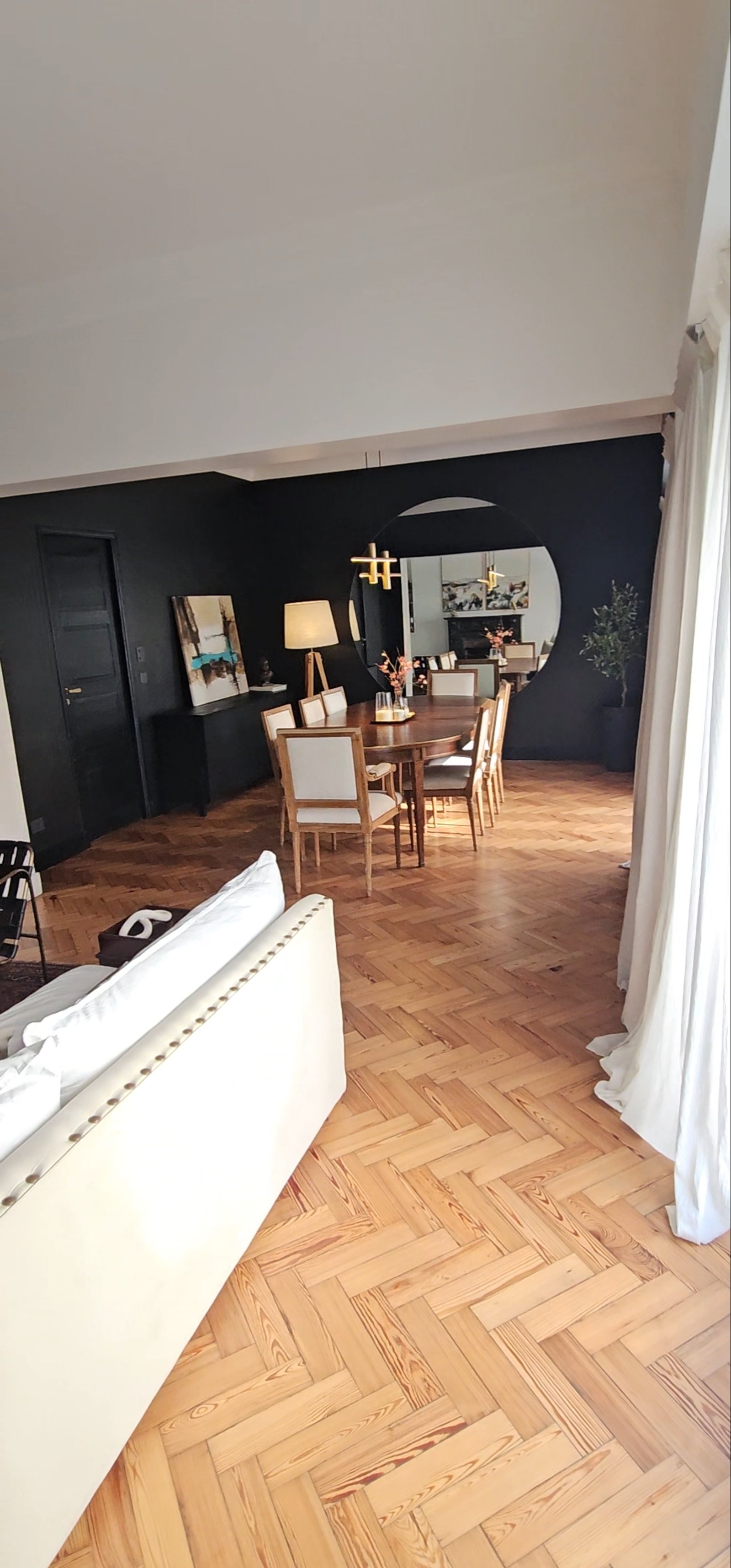 Living comedor moderno con piso de madera a espiga y espejo redondo — proyecto Cabello, por Claraboia , en Palermo