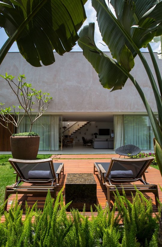 Patio minimalista con deck de madera y gran ventanal hacia casa — proyecto Arquitetura e Interiores II, por Demian Golovaty