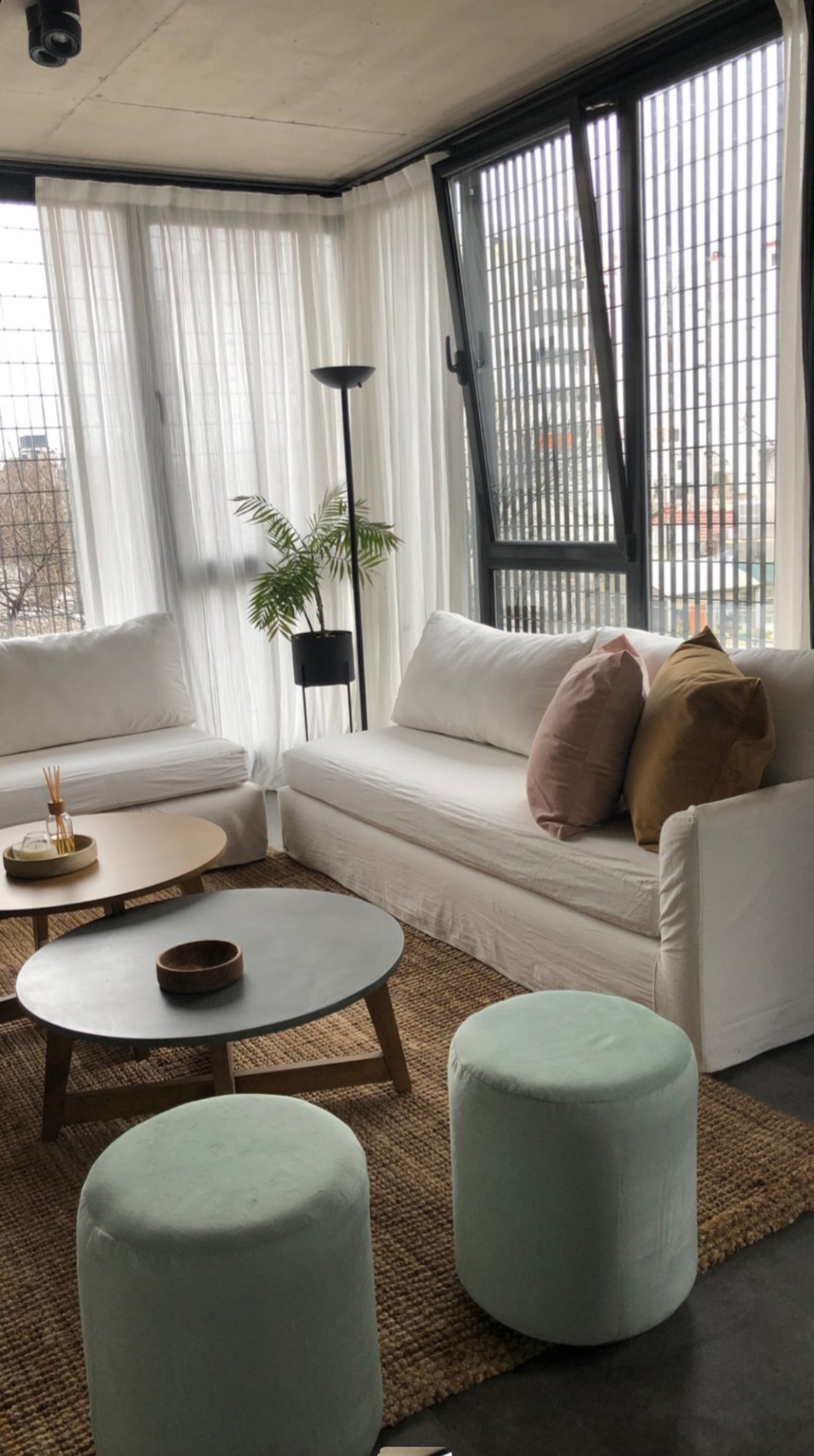 Living moderno con sillones blancos, mesas de madera y cortinas traslúcidas — proyecto Teodoro, por Claraboia , en Belgrano R