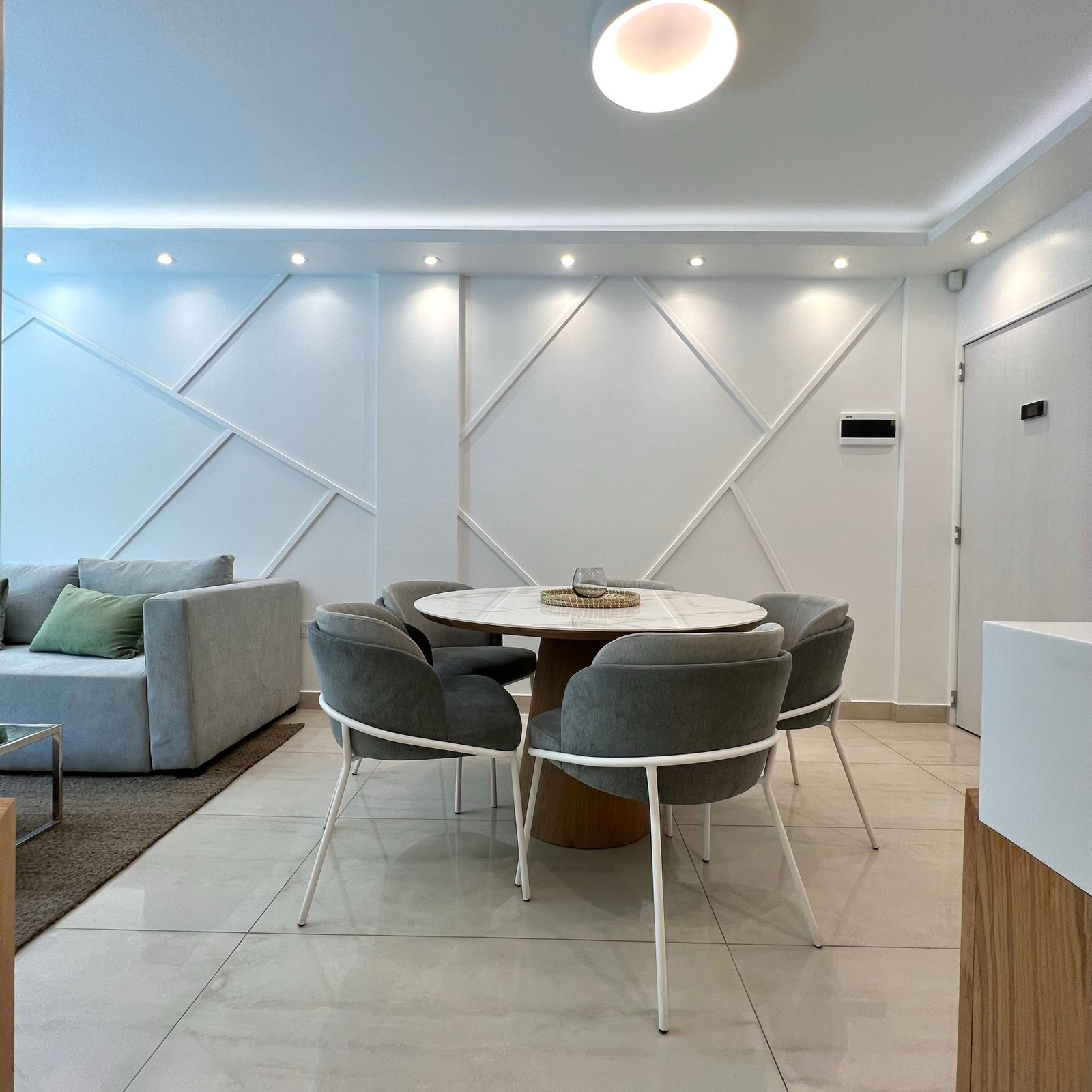 Sala de jantar moderna com painéis na parede e mesa redonda — projeto Basualdo II, por MDBK Arquitectura, em Liniers