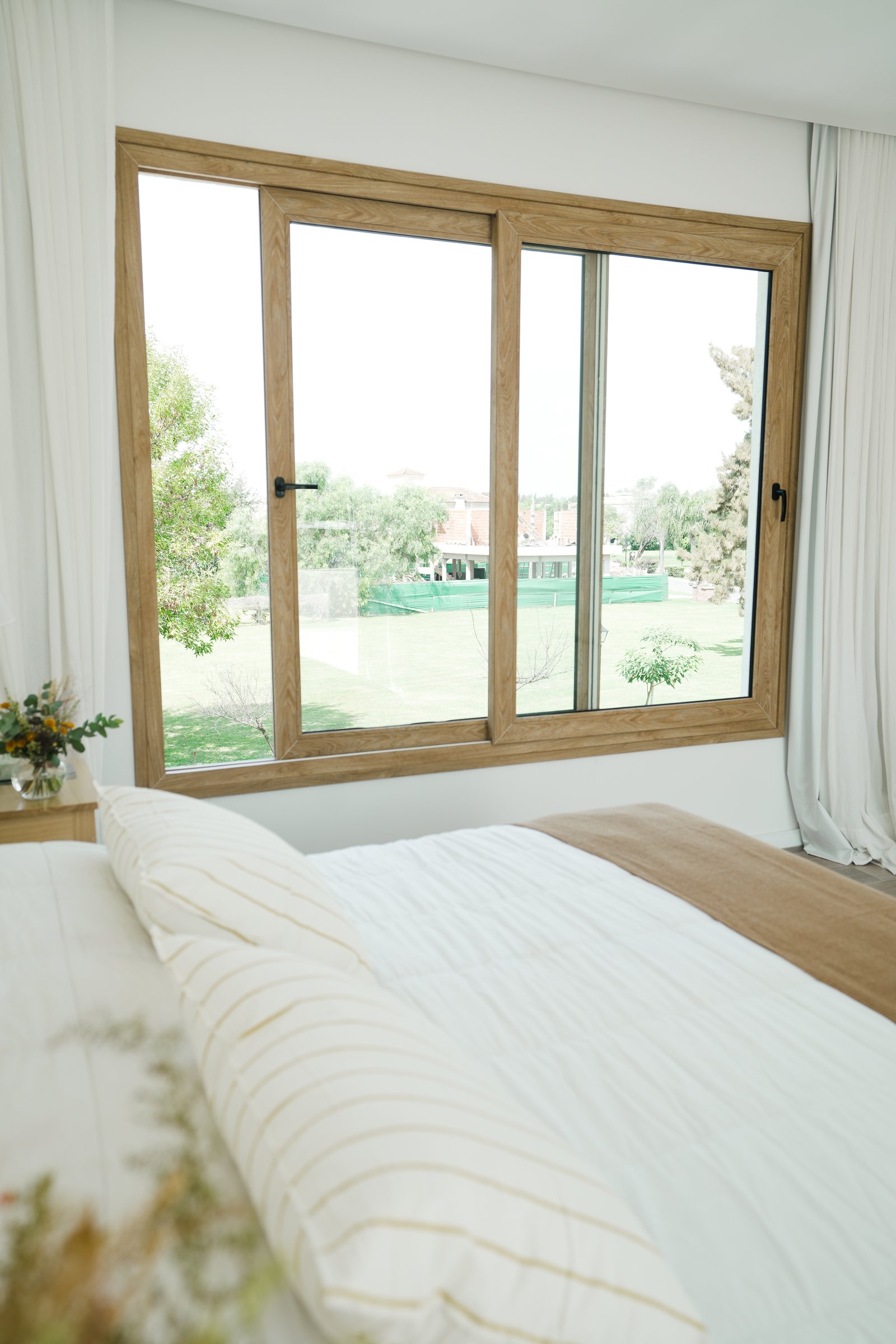 Dormitorio moderno con gran ventanal y vista al jardín — proyecto Habitaciones, por CASA1-TROMEN, en Bella Vista