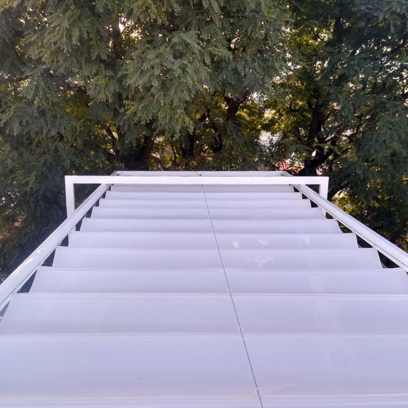 escalera moderna exterior de metal blanco entre arboles — proyecto Toldo Romano, por ToldosYa