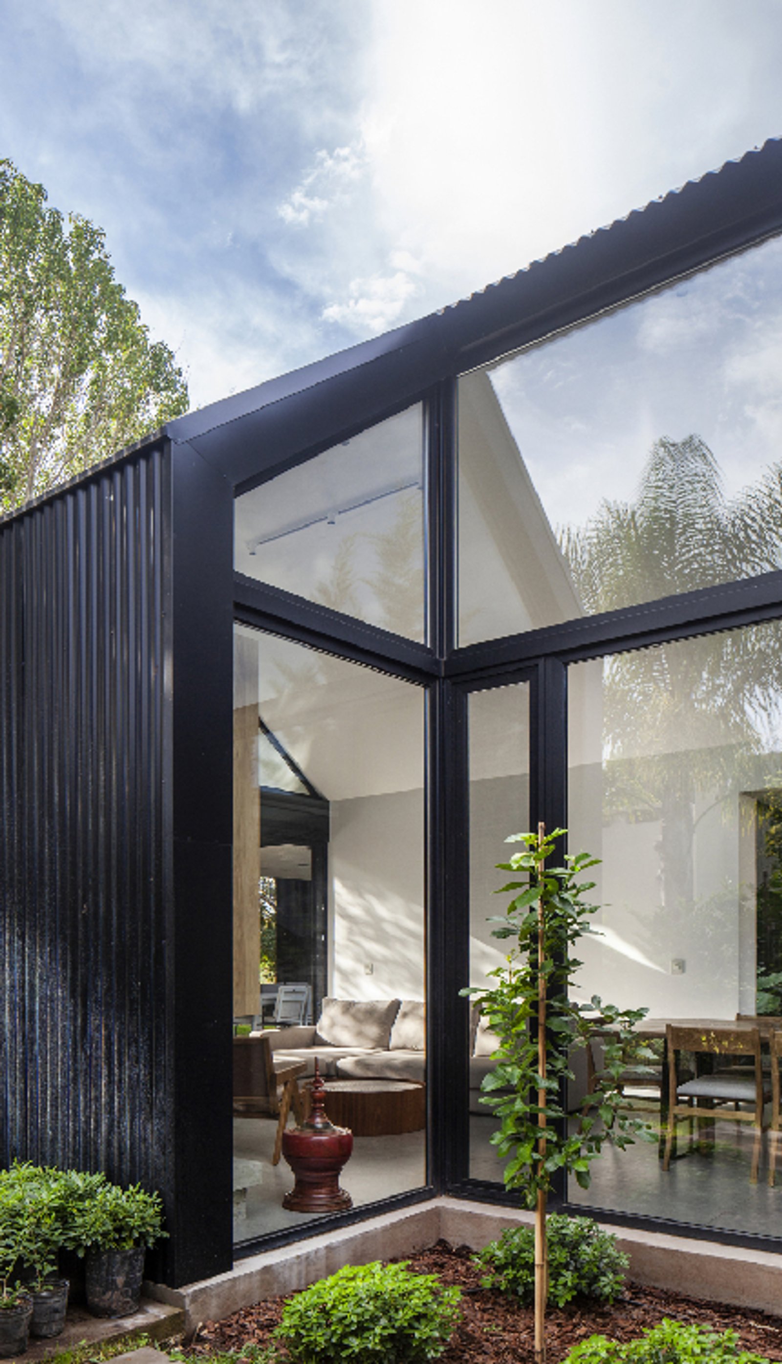 Fachada moderna con pared de chapa negra y gran ventanal de esquina — proyecto Casa Øslo, por Estudio PK, en Belén de Escobar