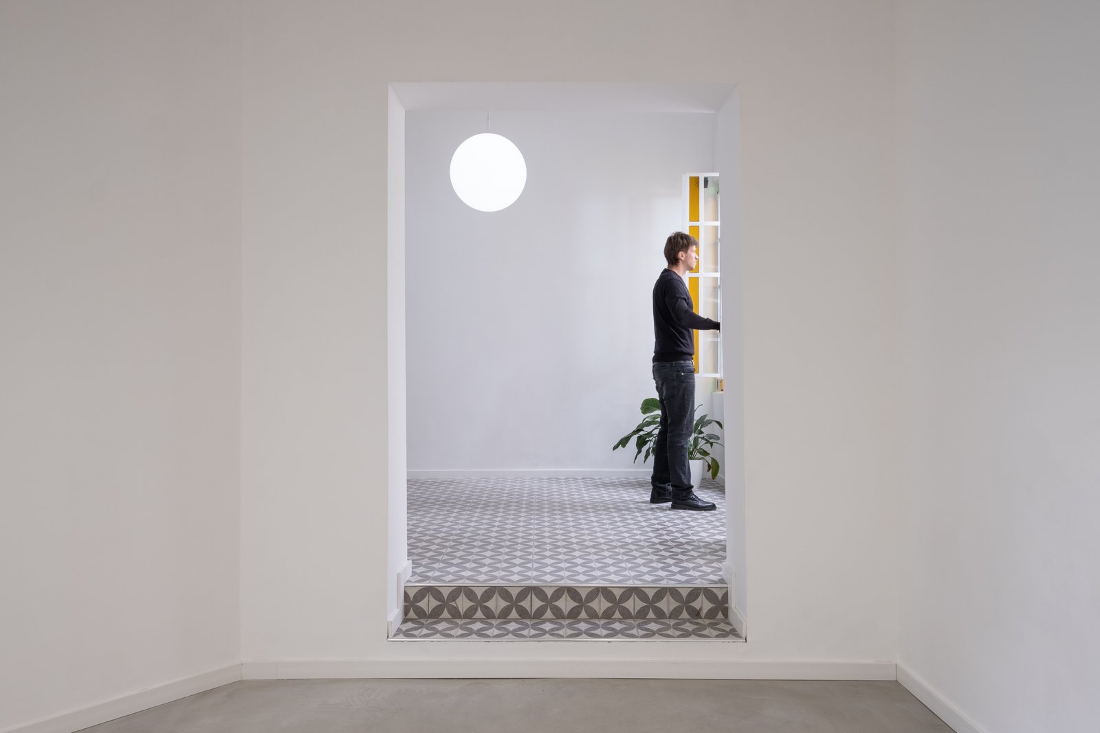 Pasillo moderno con suelo de baldosas geométricas y luz circular — proyecto Casa Patio, por Herrera Ungaro, en San Cristóbal
