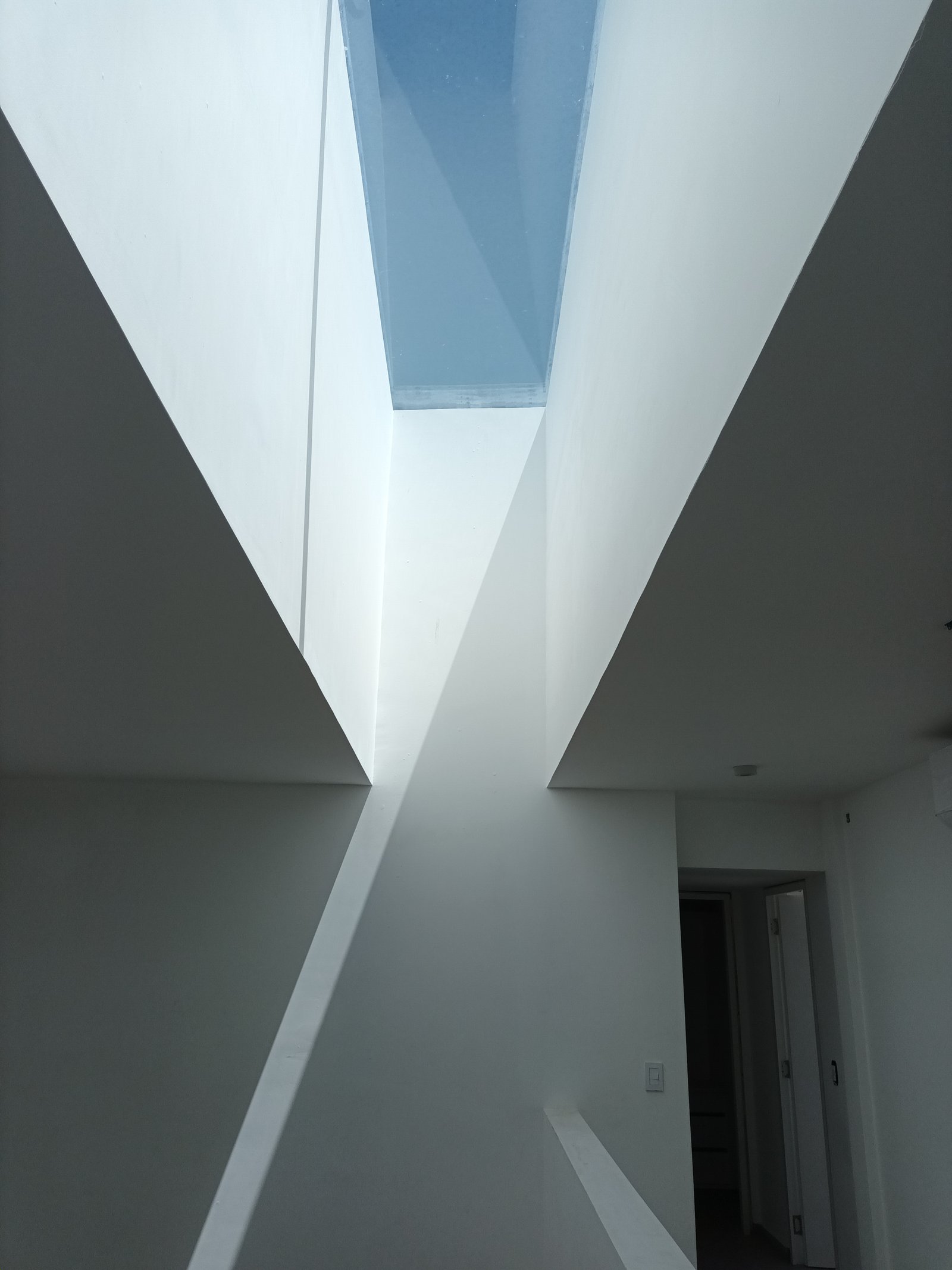 Interior moderno con tragaluz geométrico y juego de luces y sombras — proyecto CASA AA, por DIB OBRIST Arquitectas, en Ing. León Miglierini 600