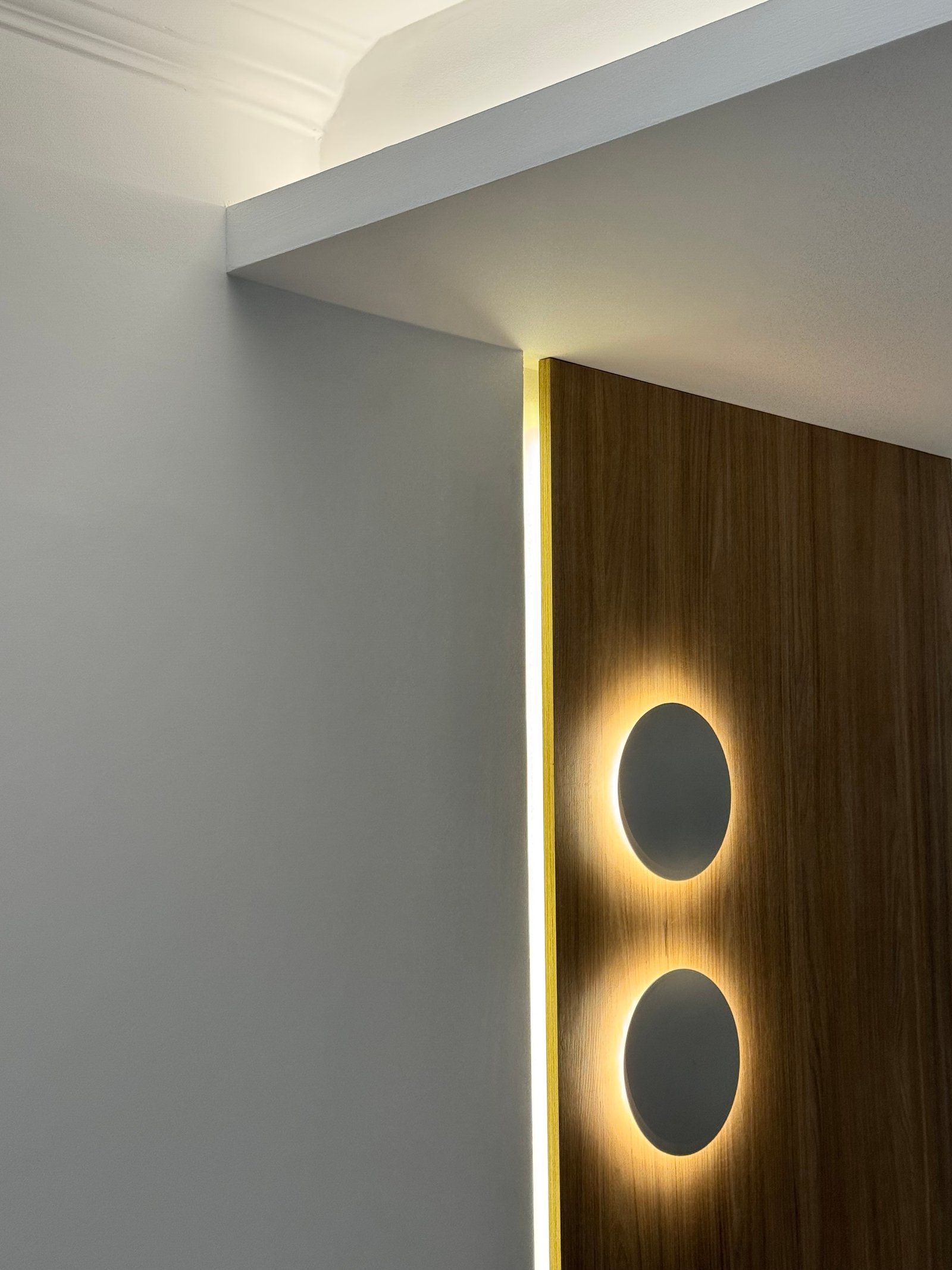 Detalle de iluminación moderna con paneles de madera y luces ovaladas — proyecto CASA LEAN, por Estudio Grupo 32, en Vicente López