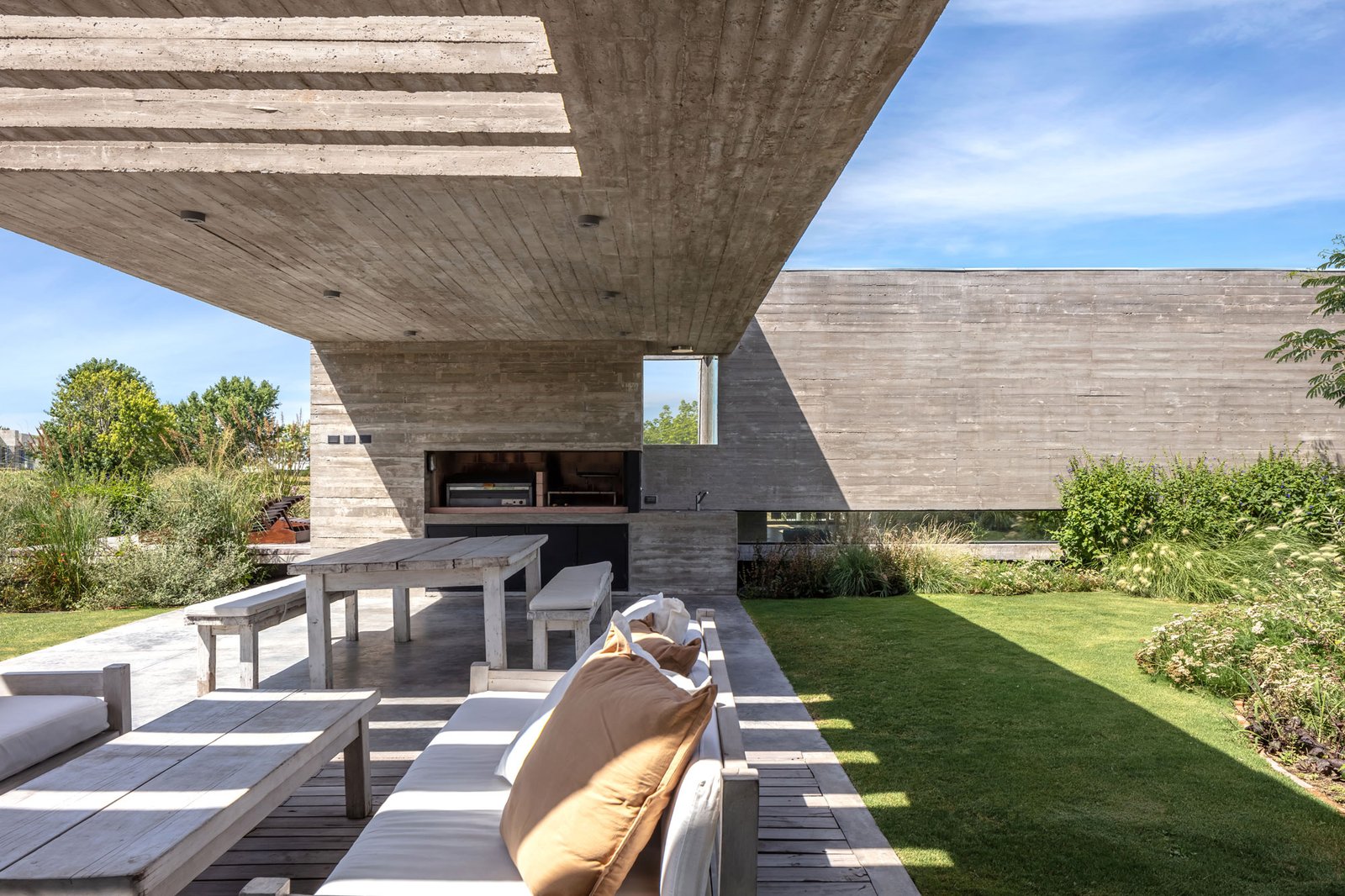 Pérgola de concreto com área de churrasqueira e deck de madeira — projeto Casa Pilará, por Besonías Almeida arquitectos, em Pilar
