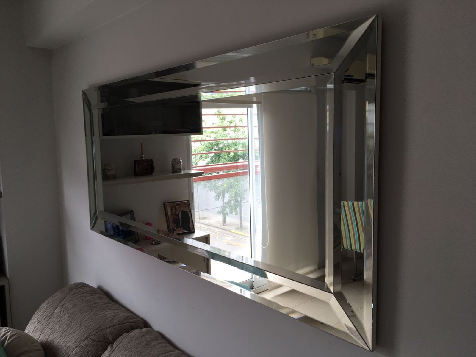 sala de estar moderna com espelho grande chanfrado — projeto Panneau espejo, por Cristalcenter, em Nordelta