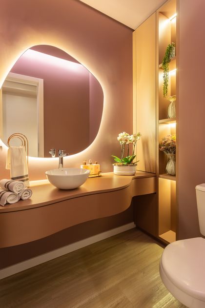 Baño moderno con espejo curvo iluminado y vanitory de madera — proyecto #ConsultórioSusanaSantin, por Oficina de Morar