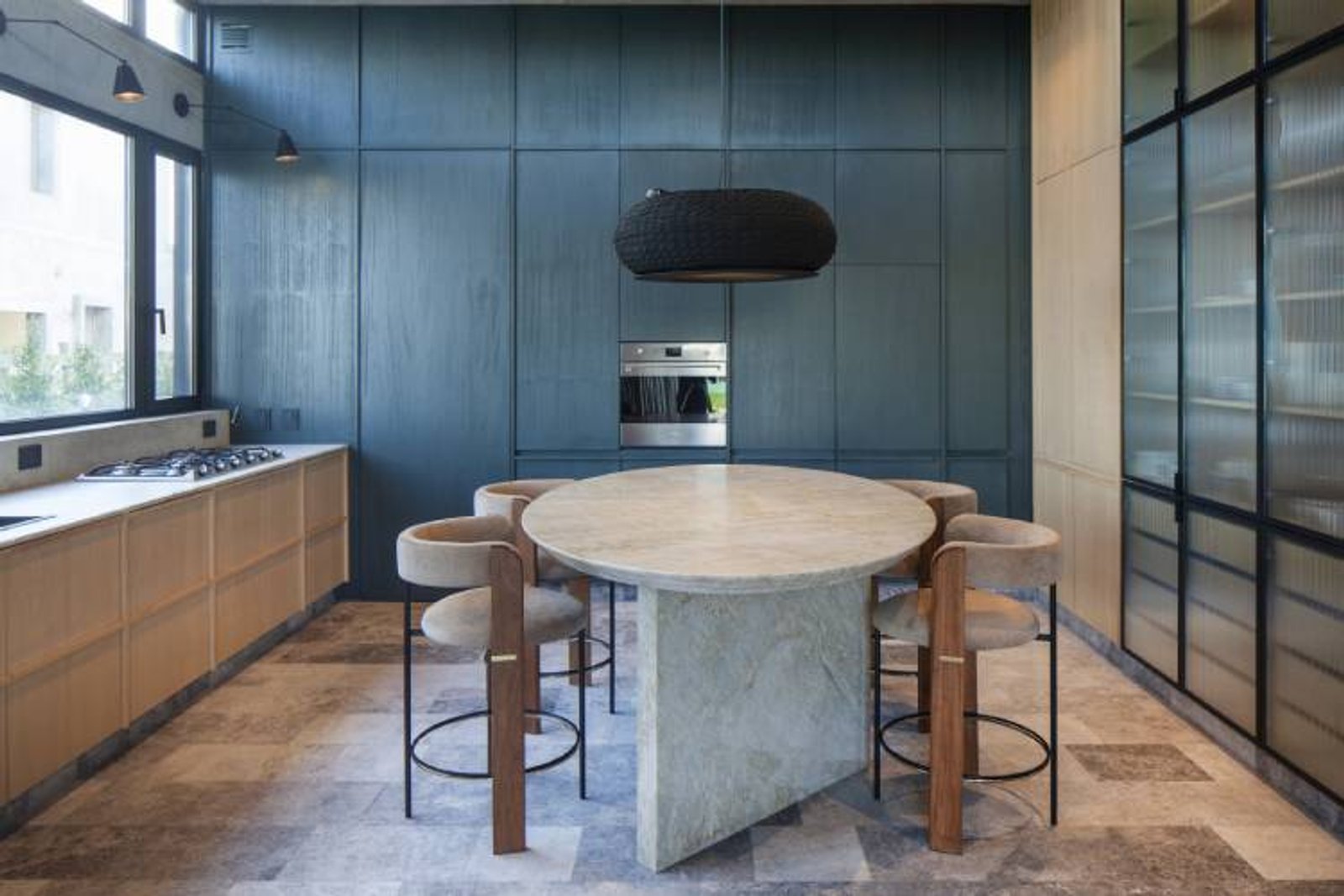 Cocina moderna con mesa de piedra, barra y paredes azules — proyecto Casa Órbita, por Estudio PK, en Nordelta