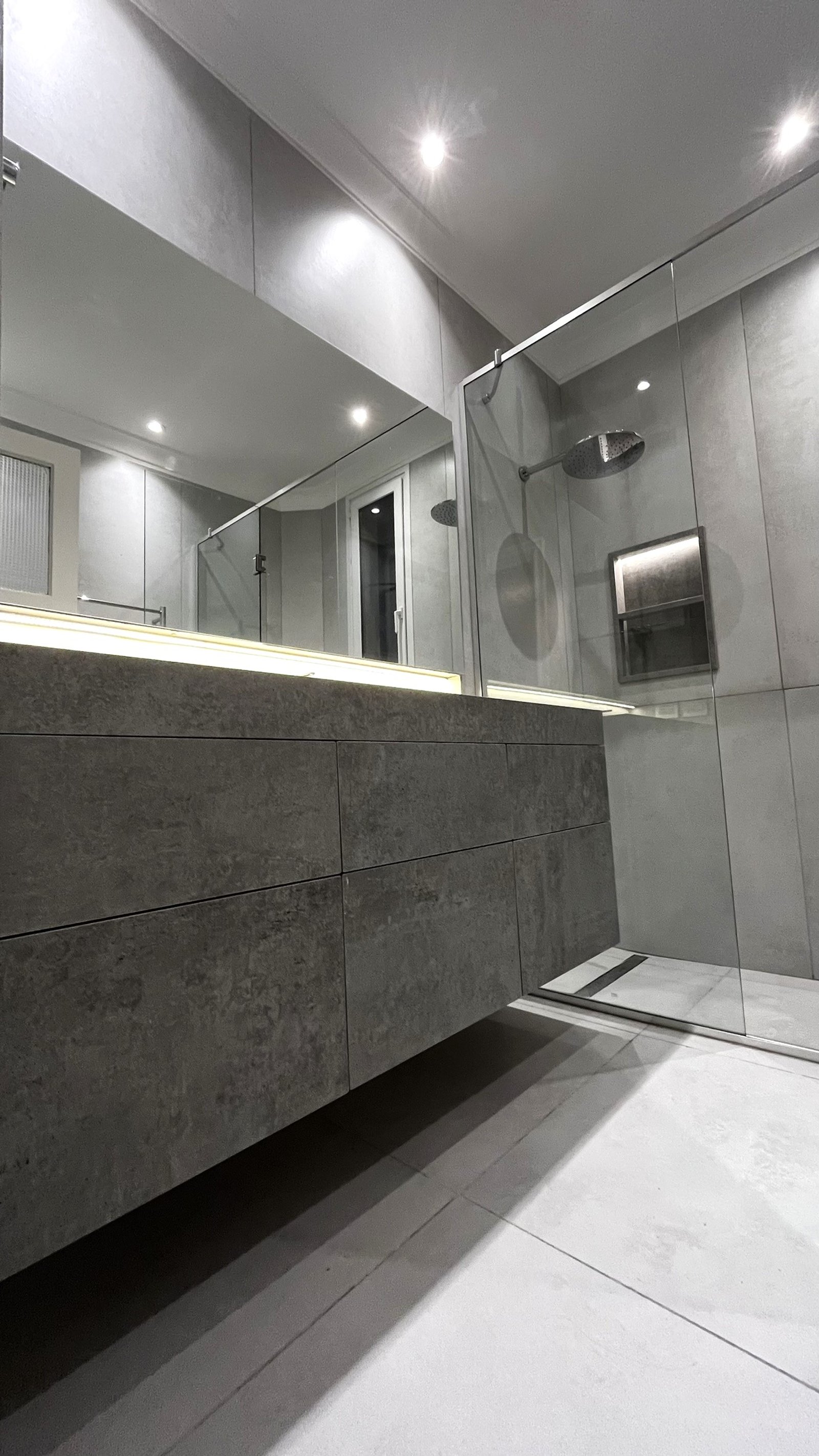 Baño moderno con vanitory gris, espejo grande y ducha de vidrio — proyecto CASA CERRITO (German Salas arquitectura), por German Salas arquitectura - San Isidro, en Buenos Aires