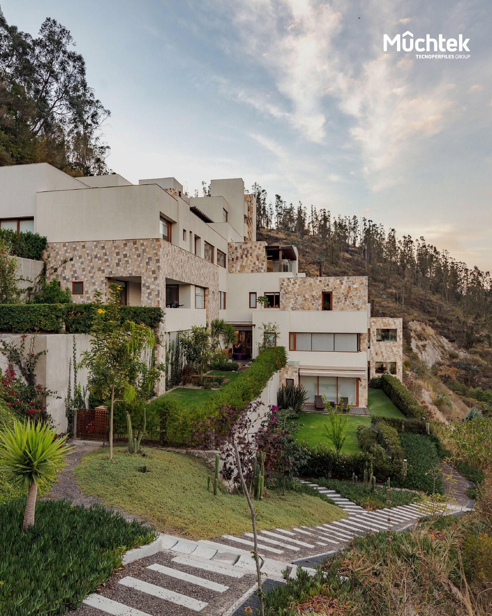 Fachada moderna en montaña con piedra y vegetación exuberante — proyecto Edificio Anezi, por MUCHTEK, en Cumbayá