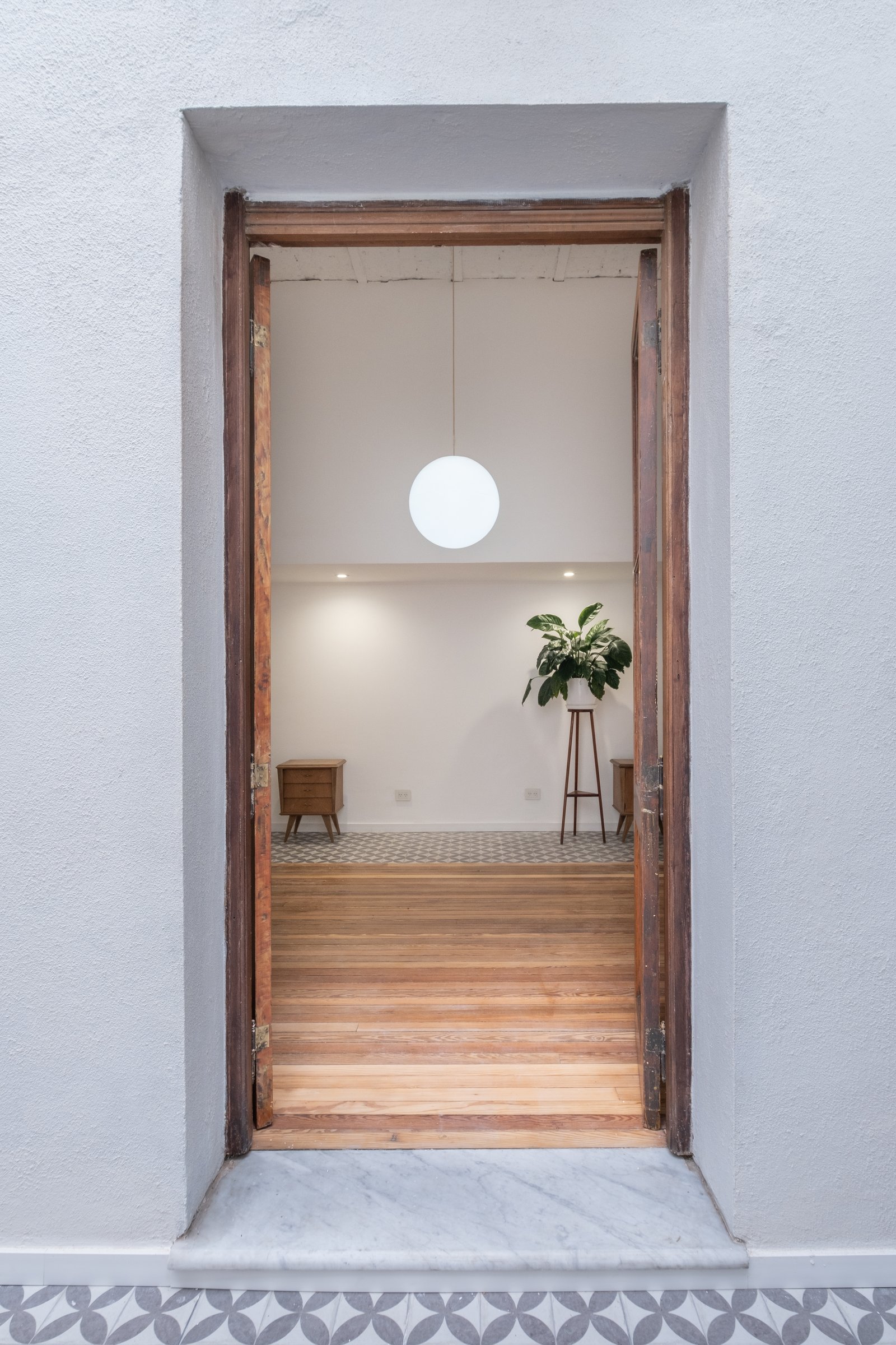 interior moderno con luz esférica y puertas abiertas — proyecto Casa Patio, por Herrera Ungaro, en San Cristóbal
