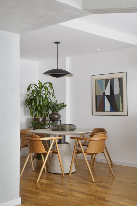 Comedor minimalista con mesa redonda, sillas de cuero y plantas decorativas — proyecto Projeto Barão da Torre, por Kelly Figueiredo Arquitetura