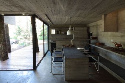 Quincho moderno con parrilla, mesada hormigón y grandes ventanales — proyecto Casa Franz, por Luciano Kruk