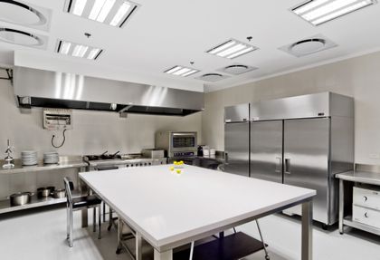 Cocina industrial profesional con isla central y equipamiento de acero inoxidable — proyecto Oficina B, por Estudio Dado, en Puerto Madero