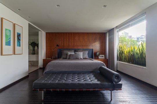 Dormitorio contemporáneo con pared terracota, cama king y banco de cuero negro — proyecto APARTAMENTO FL, por Frederico Bicalho Arquitetura