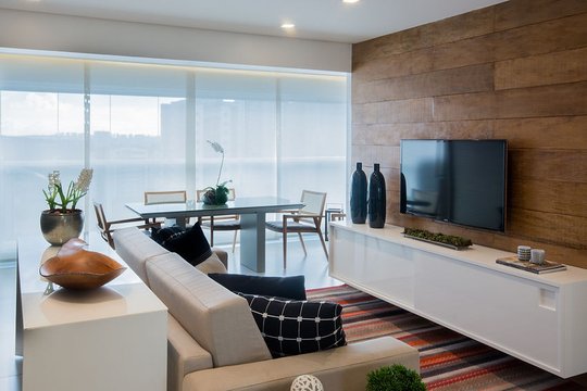 living moderno con pared madera, ventanal panoramico y vista al mar — proyecto Studio Pinheiros, por Bordin E Soares Interiores