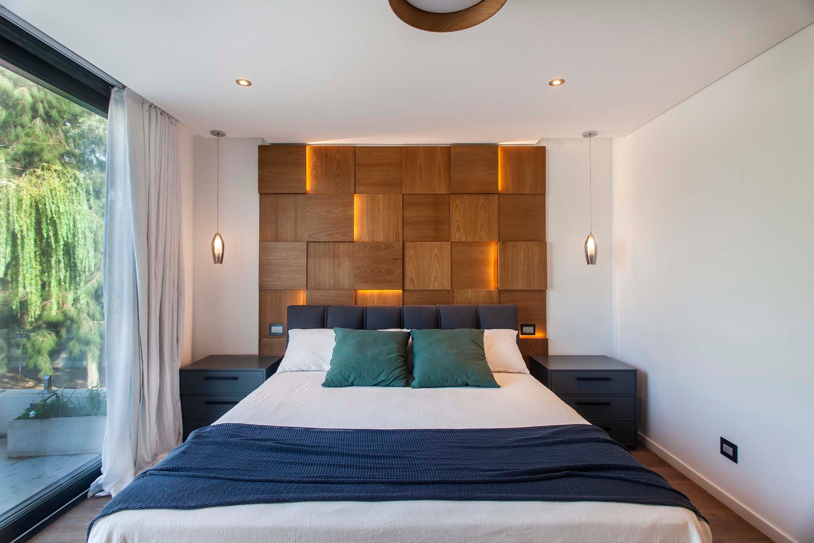 Dormitorio moderno con pared de madera geométrica e iluminación indirecta — proyecto CASA T199, por A'PRIMA - Arquitectura Sustentable, en Los Robles 5901