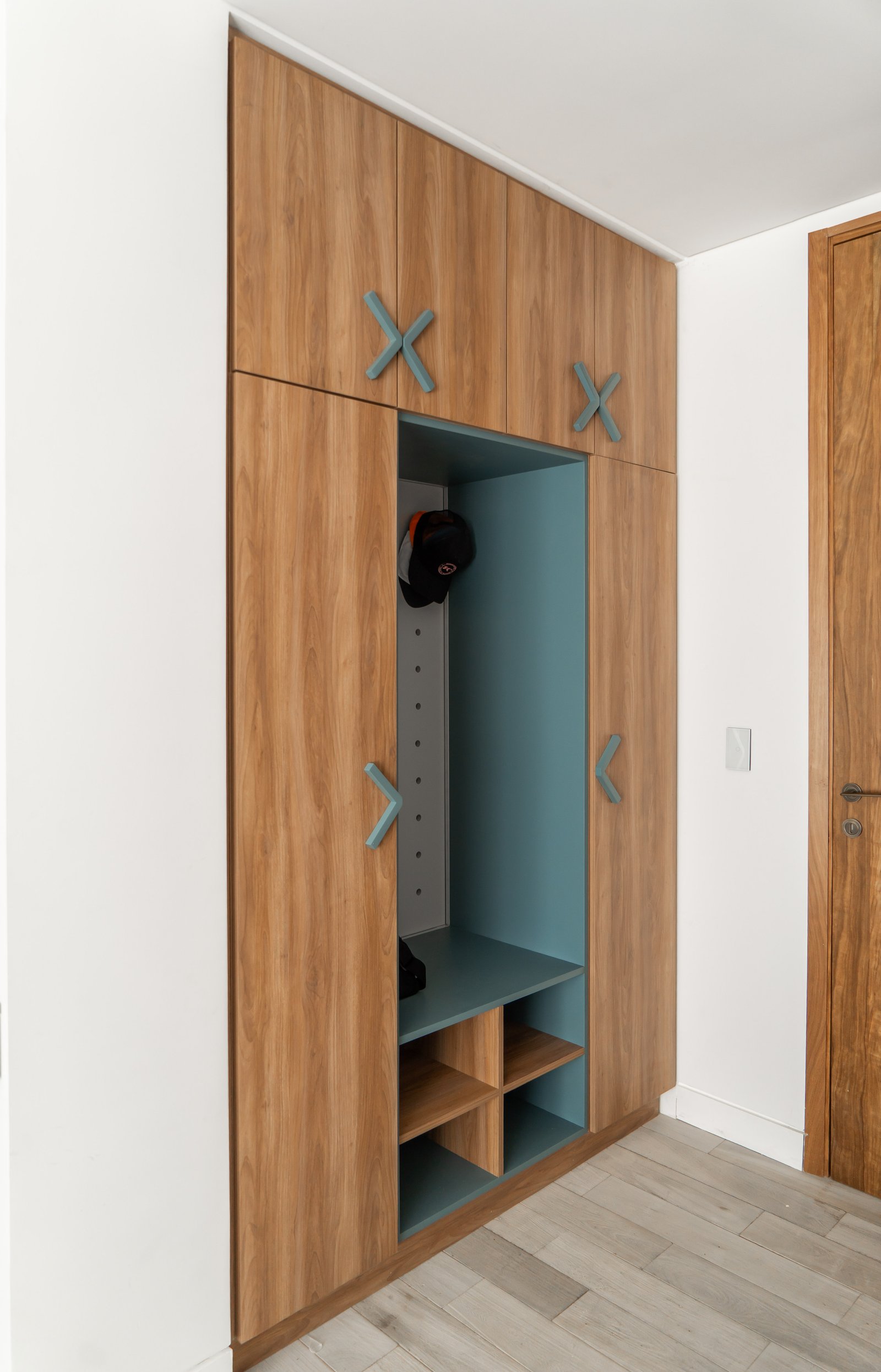 Entrada moderna con mueble de guardado de madera y detalles en verde azulado — proyecto PROYECTO NAUDIR II, por July Acosta Home, en Belén de Escobar
