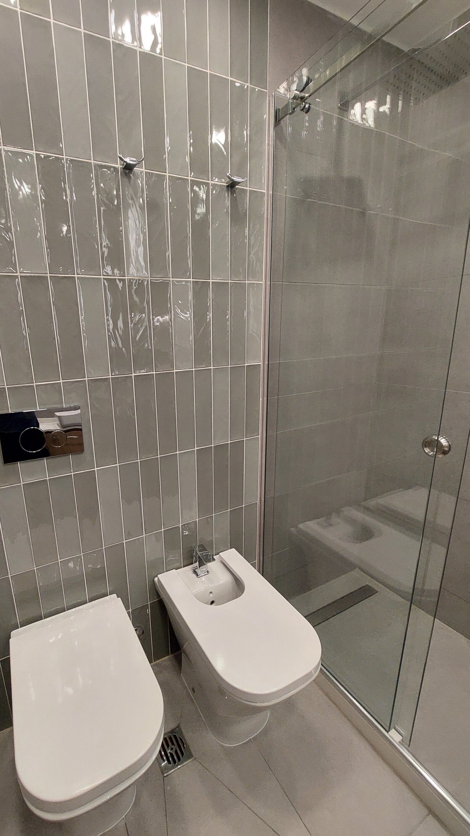 Baño moderno con bidet e inodoro, azulejos grises — proyecto FLORES, por Arquitecta, en Flores