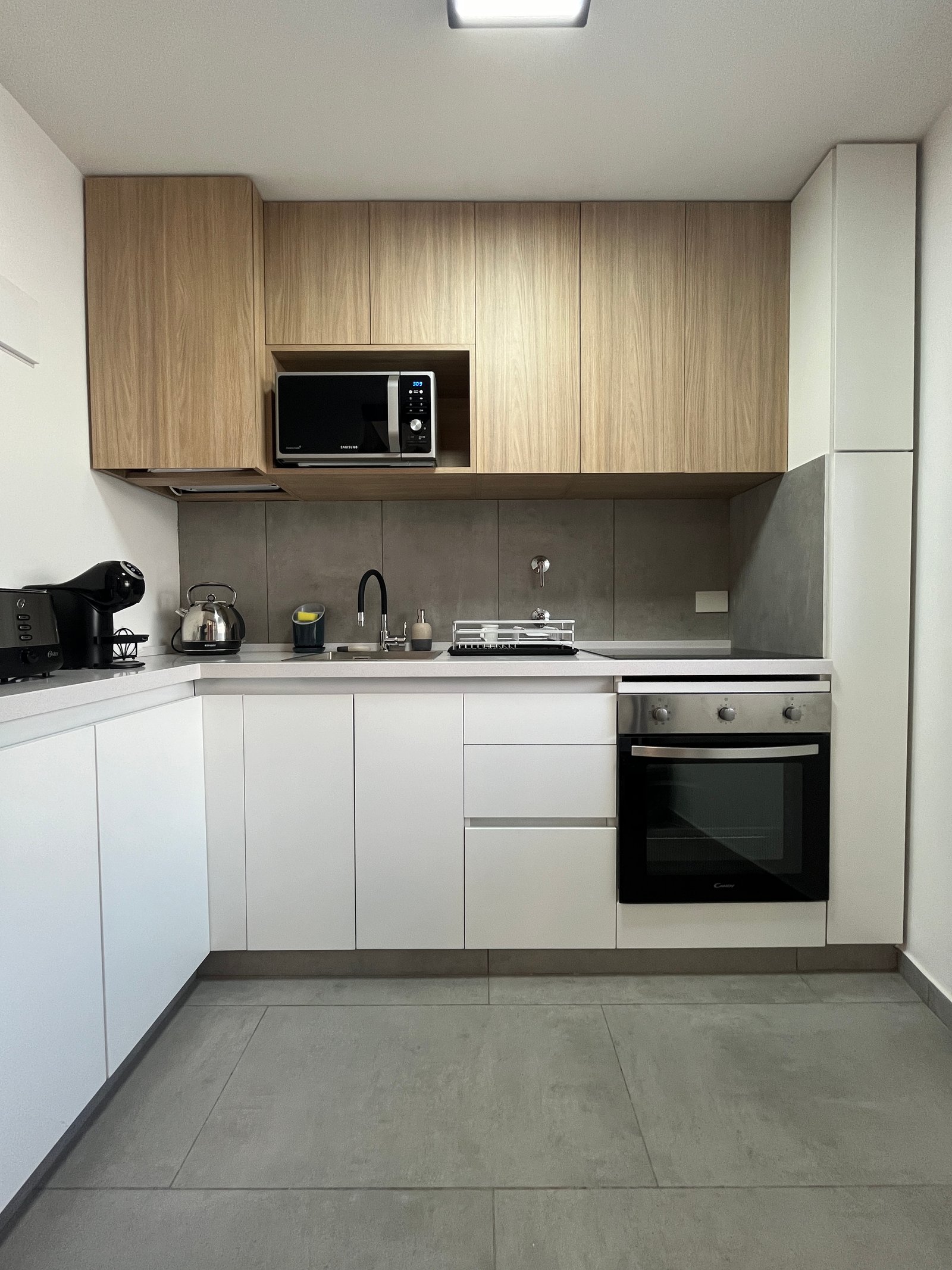 Cocina moderna escandinava con muebles de madera y blancos, electrodomésticos integrados y suelo de piedra — proyecto Departamento Puerto Madero, por Arcucci Arquitectura, en Puert