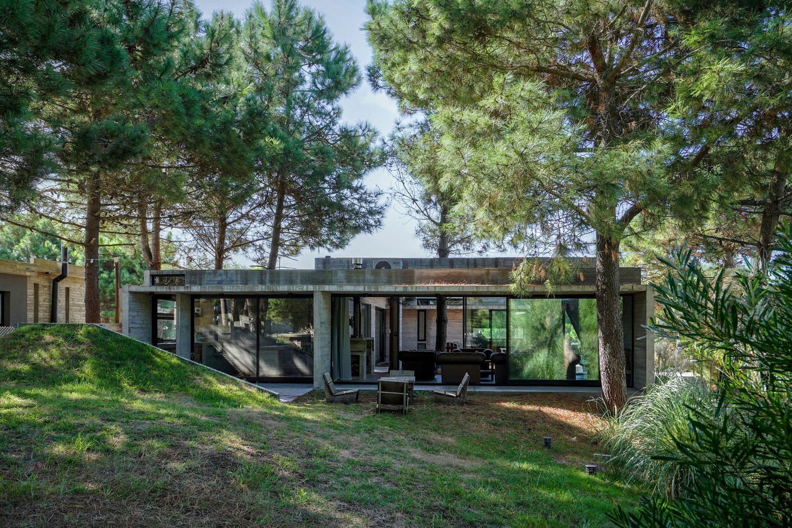 fachada moderna de hormigón con grandes ventanales y pérgola — proyecto Casa Loma, por Besonías Almeida arquitectos, en X6VF+67