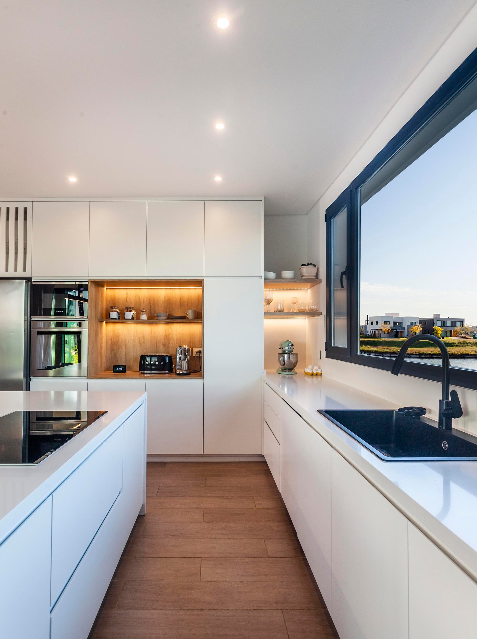 Cocina moderna minimalista con vista al mar y mobiliario blanco — proyecto CASA C313, por A'PRIMA - Arquitectura Sustentable, en Provincia de Buenos Aires