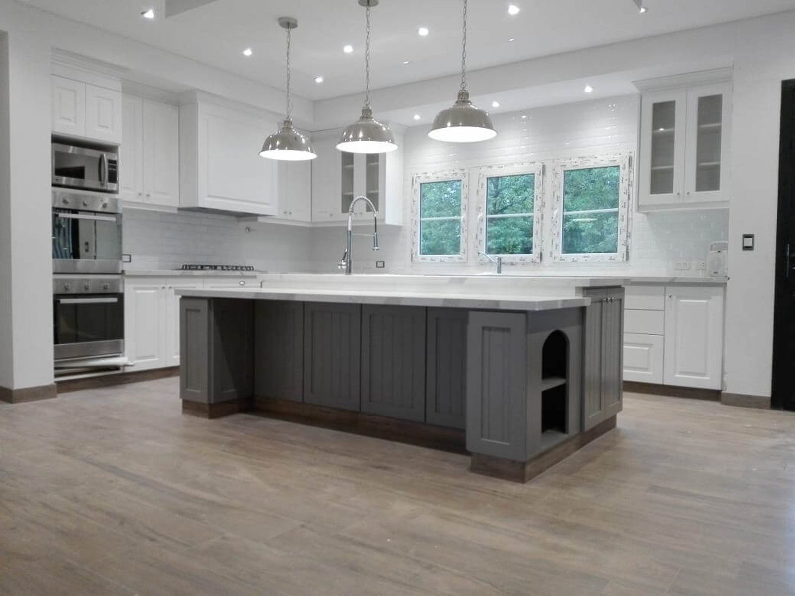 Cocina moderna con isla grande gris y gabinetes de madera — proyecto Línea Praga, por Casa Leiro