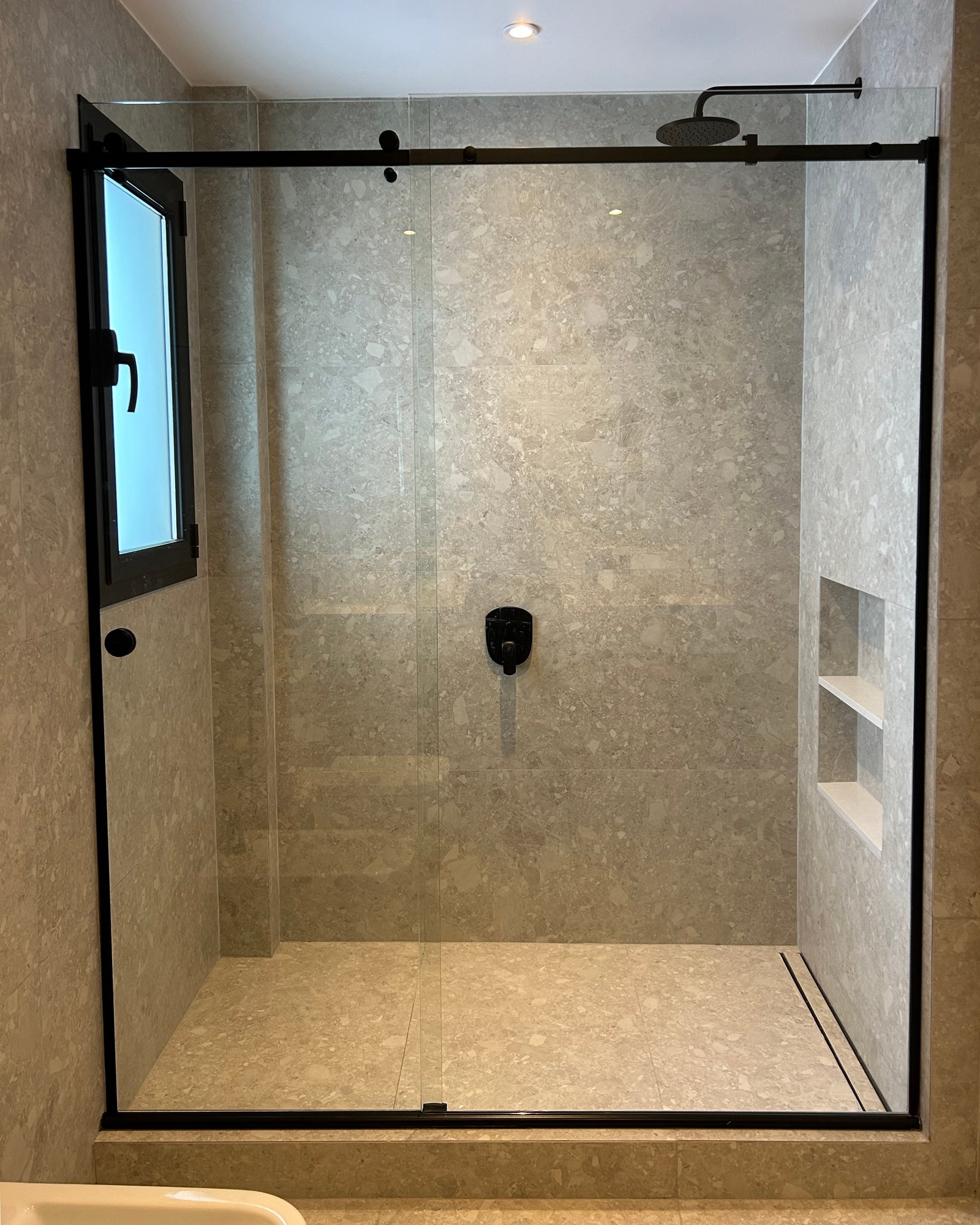 Banheiro moderno com box de vidro sem moldura e azulejos de pedra — projeto LIBERTADOR II, por ESTUDIO TEZ, em Palermo