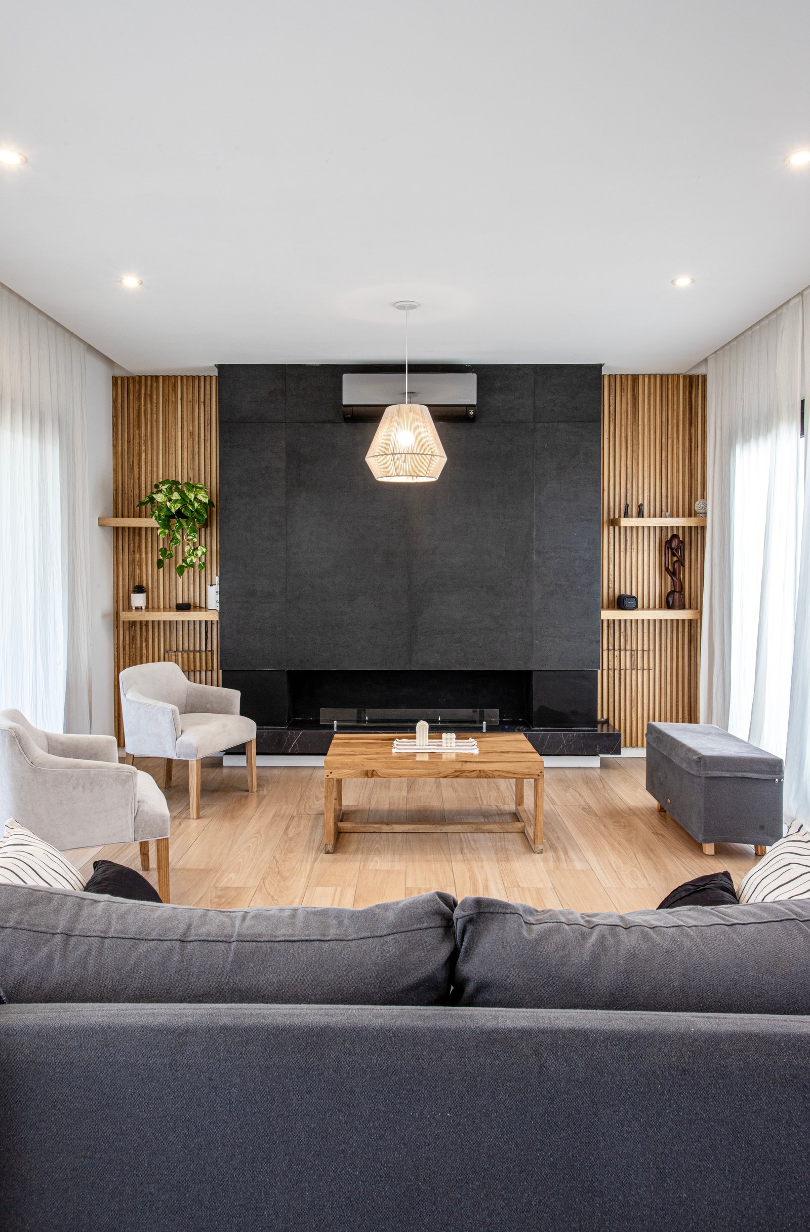 Sala de estar moderna com lareira de pedra e parede de ripas de madeira — projeto SS45, por EZ architects, em Pilar