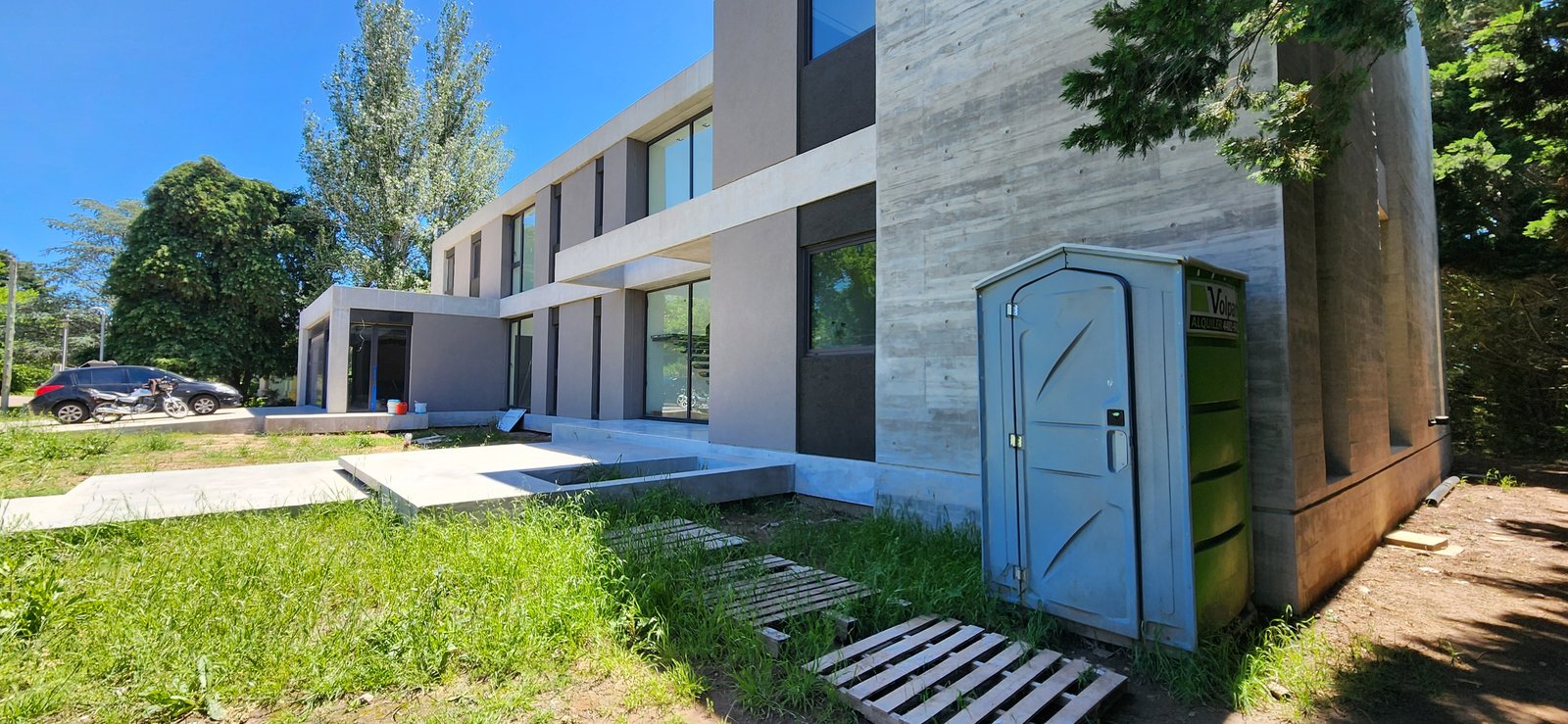 fachada moderna de hormigón visto con baño portátil — proyecto Casa CAD, por Estudio Rifahi, en Moreno