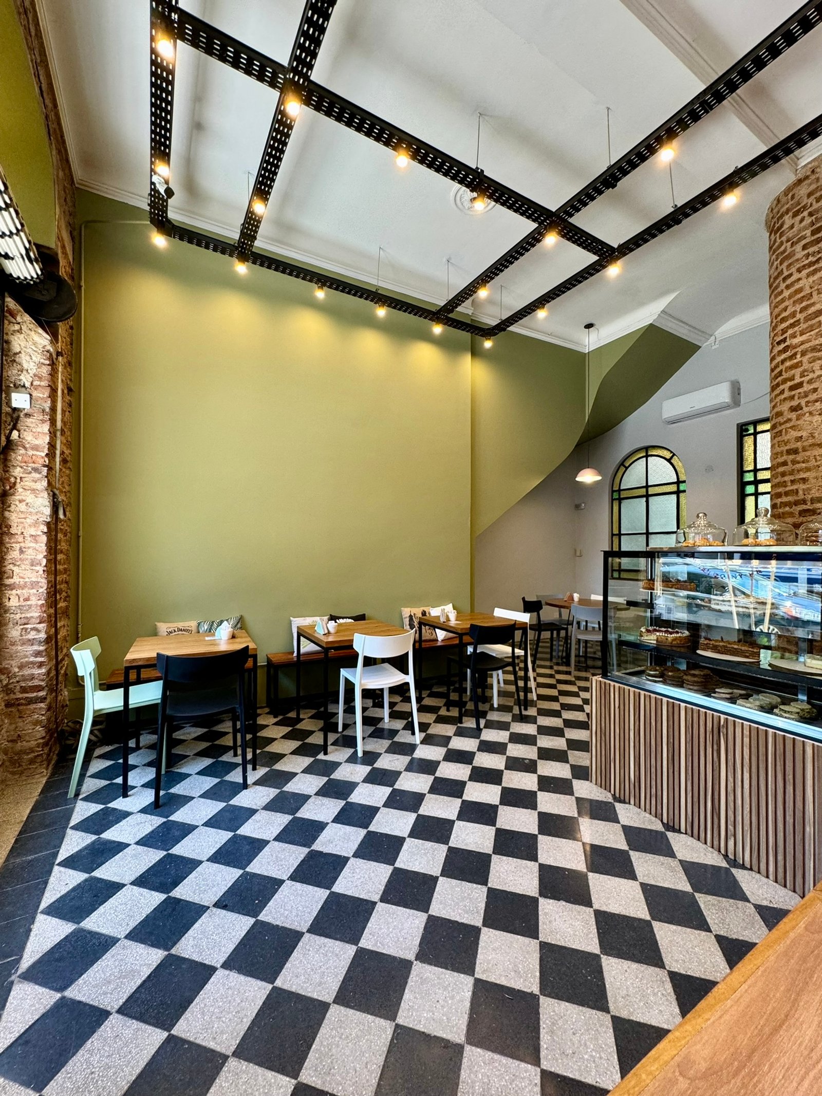 Cafetería moderna con piso ajedrezado y luces industriales — proyecto UGA Coffee House, por MDBK Arquitectura, en Almagro