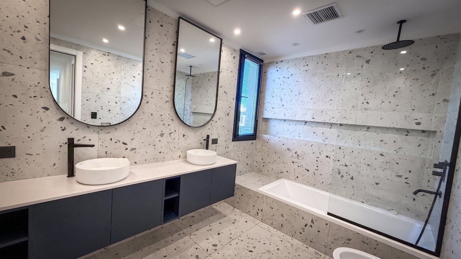 Baño moderno con paredes y suelo de terrazo, dos lavabos ovales y grifería negra — proyecto Yatch 278, por CIFARELLI arquitectos, en Tigre