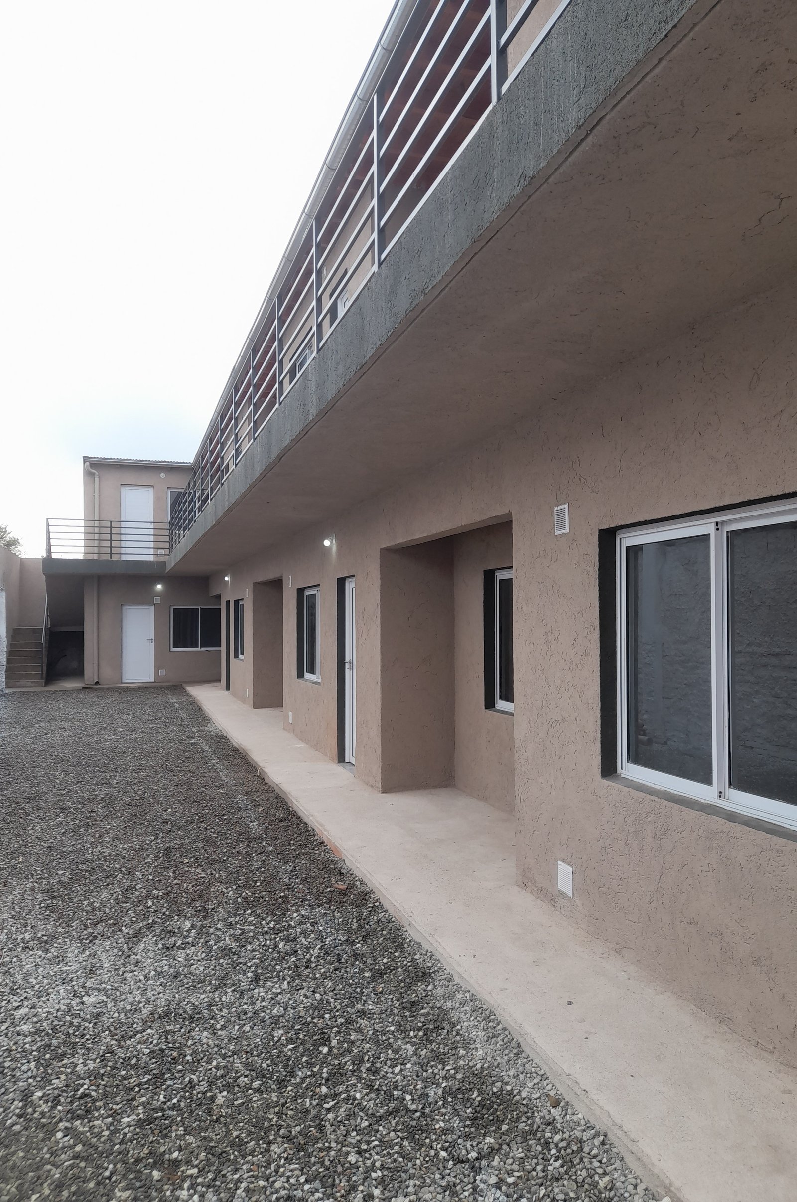 Edificio residencial en construcción con balcón y patio de grava — proyecto Departamentos, por CN Construcciones, en Alta Gracia