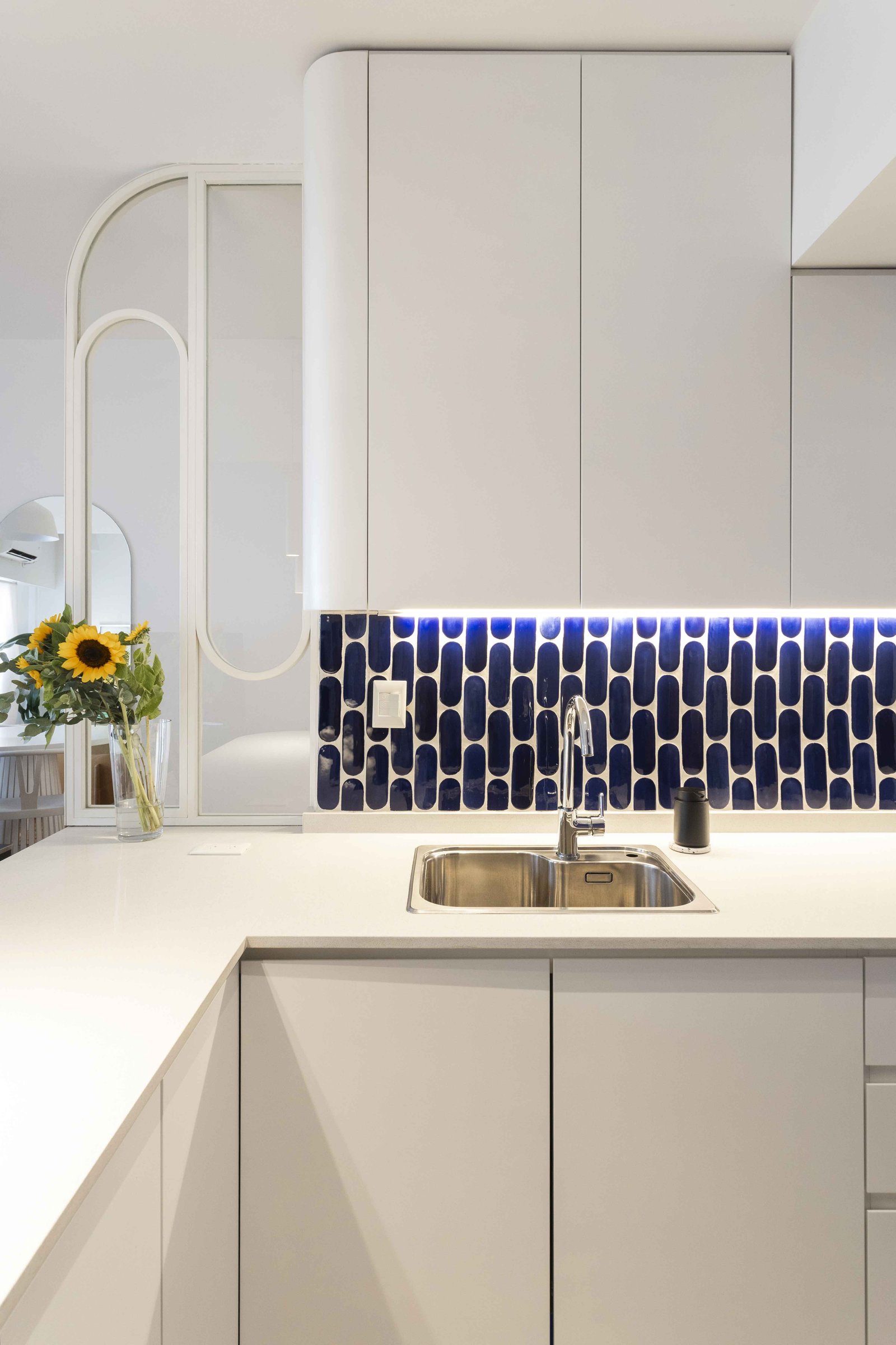 Cozinha moderna branca com azulejos azuis e girassóis — projeto Julián Alvarez, por Bouré Studio, em Palermo