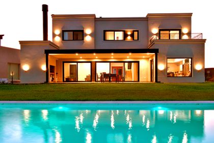 Fachada moderna con piscina iluminada y deck de madera — proyecto Casa CG191, por EZ architects, en Belén de Escobar