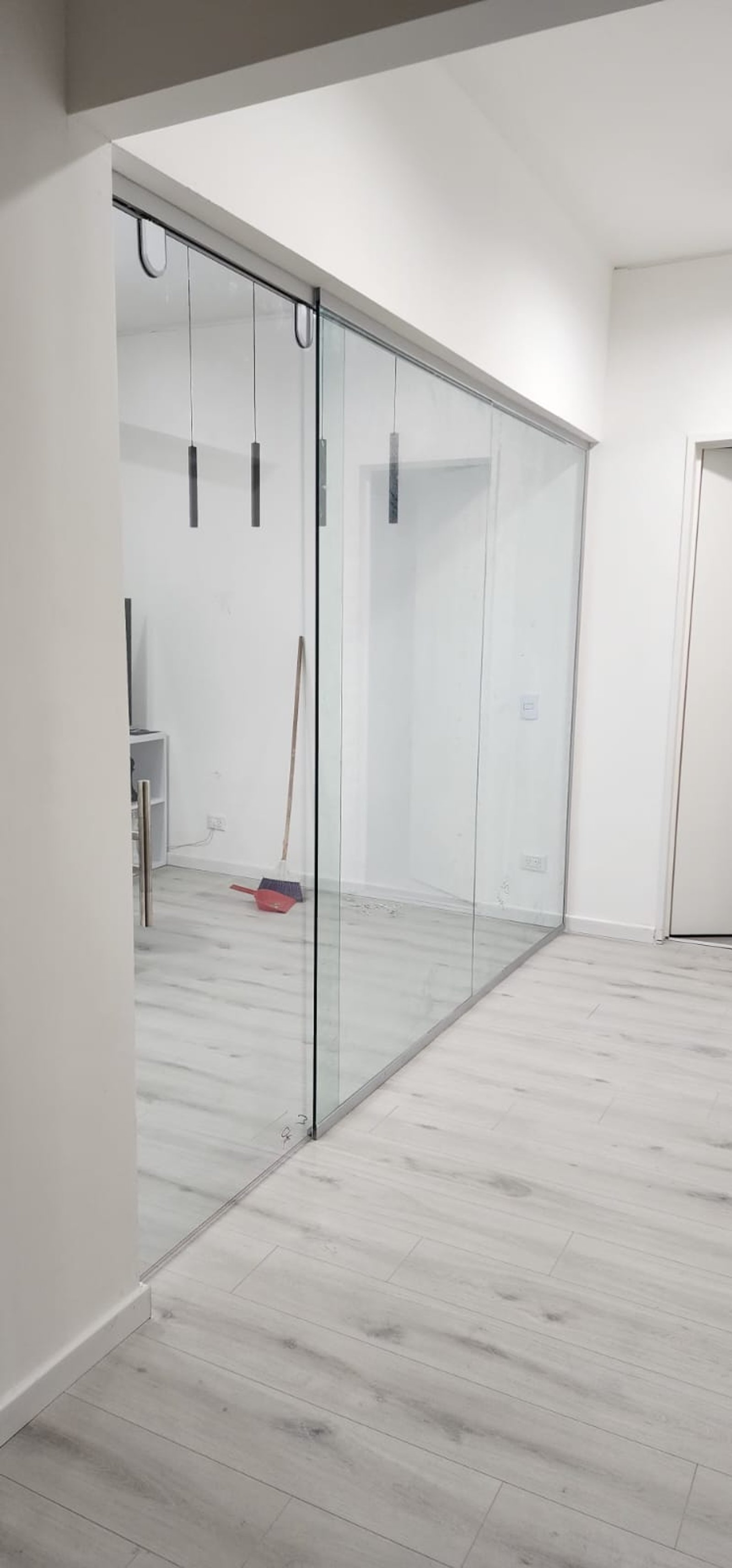 Sala de estar moderna com divisória de vidro e piso de madeira claro — projeto Frente corredizo + paños fijos, por Cristalcenter, em Nordelta