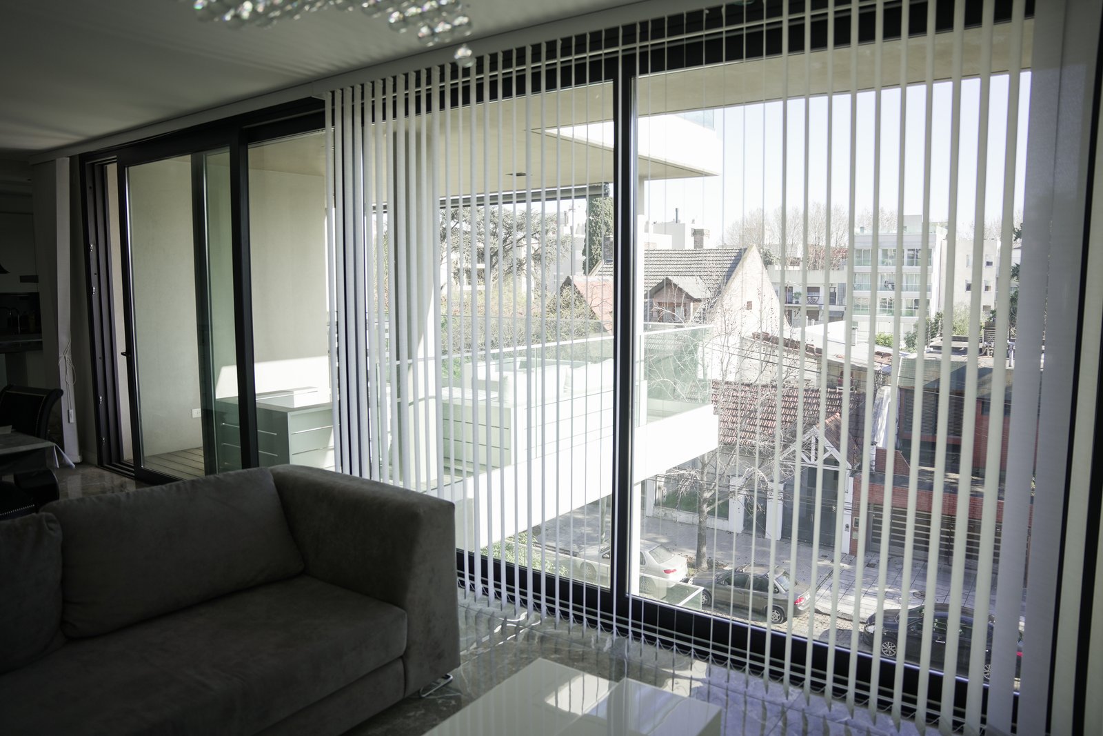 Living moderno con grandes ventanales y sofá beige — proyecto JLC Residences, por MUCHTEK, en Buenos Aires