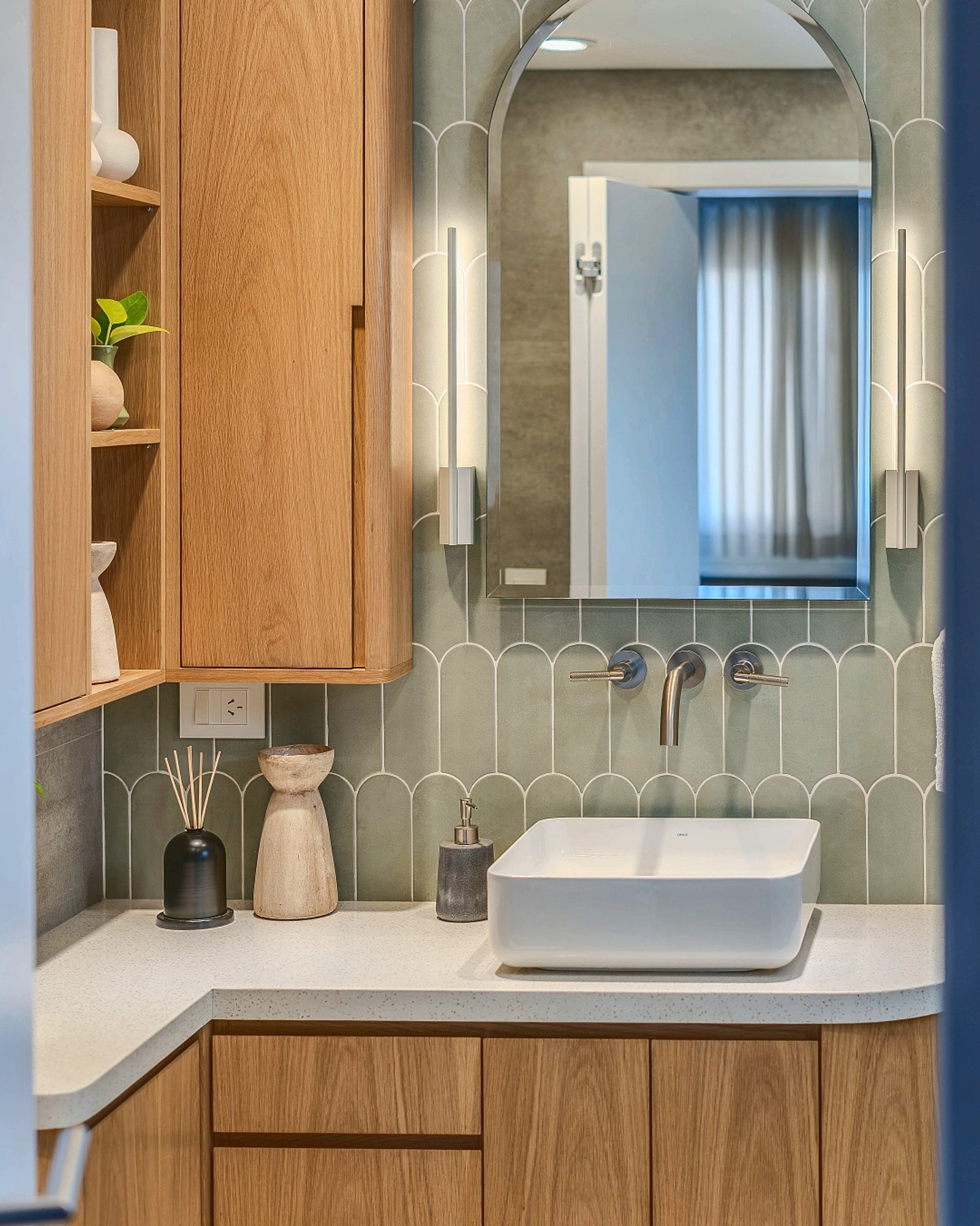 Banheiro moderno com móveis de madeira e azulejos curvos — projeto Quesada, por Blue Rabbit Design, em Núñez