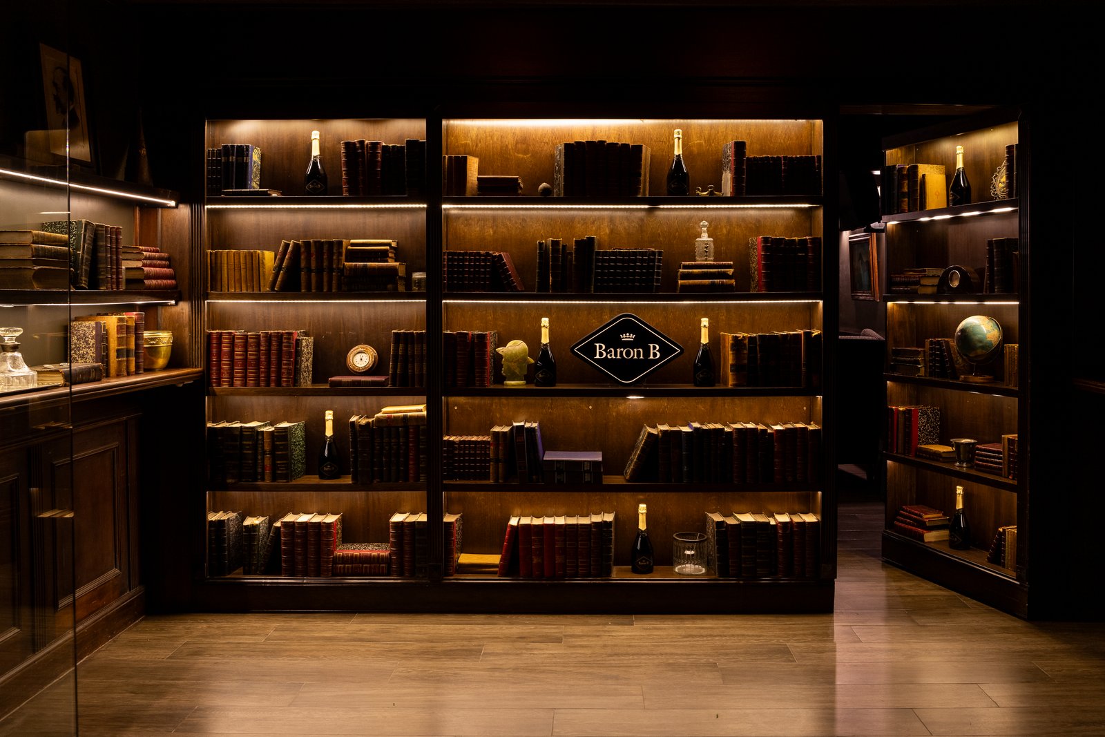 Estantes de madeira escura com livros, iluminação quente e ambiente de biblioteca — projeto PRESIDENTE BAR HIPODROMO, por AB ARQUITECTURA, em San Isidro