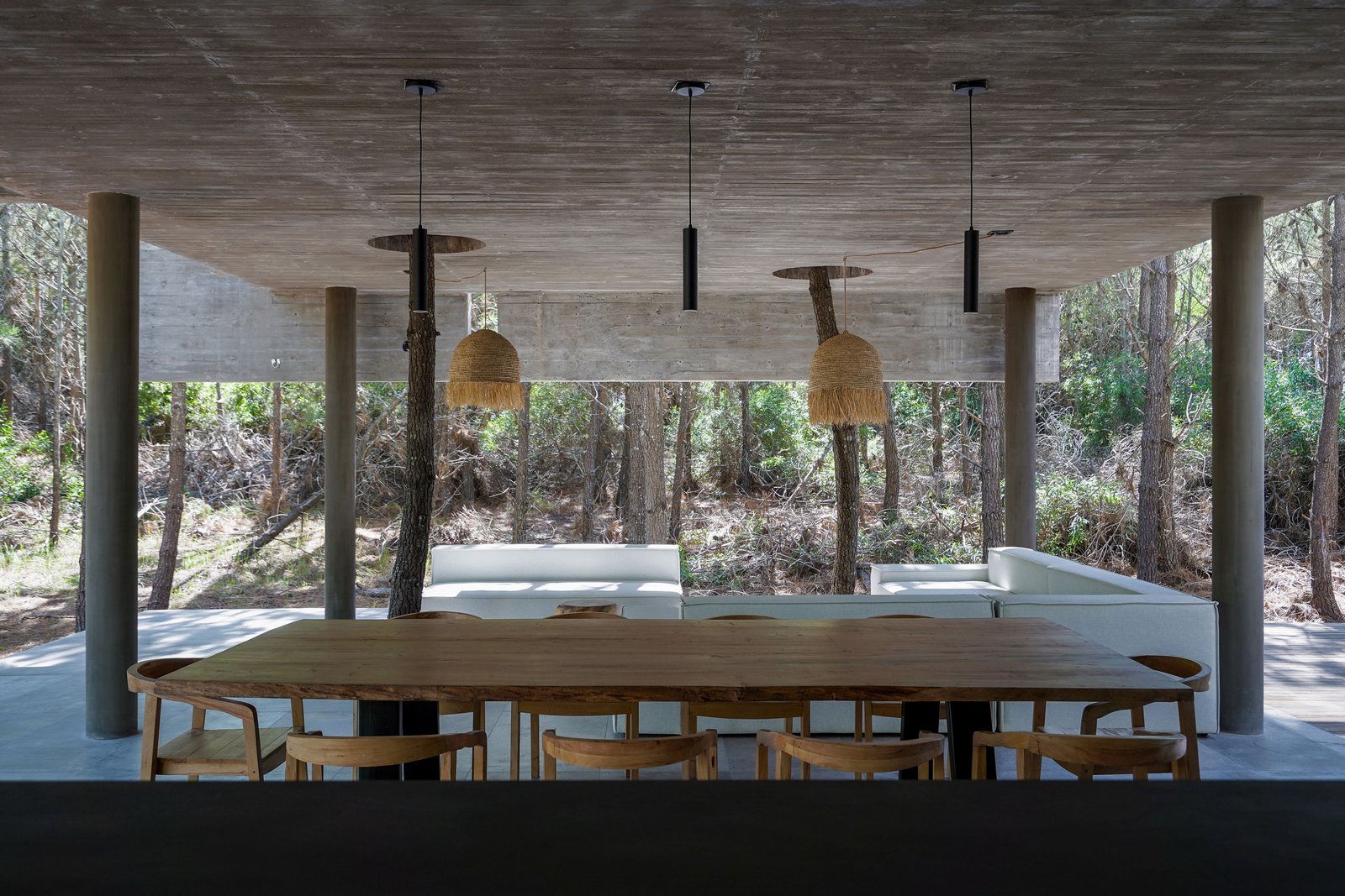 Comedor exterior con mesa de madera y sillas de ratán — proyecto Casa 4H, por Besonías Almeida arquitectos, en X6VF+67