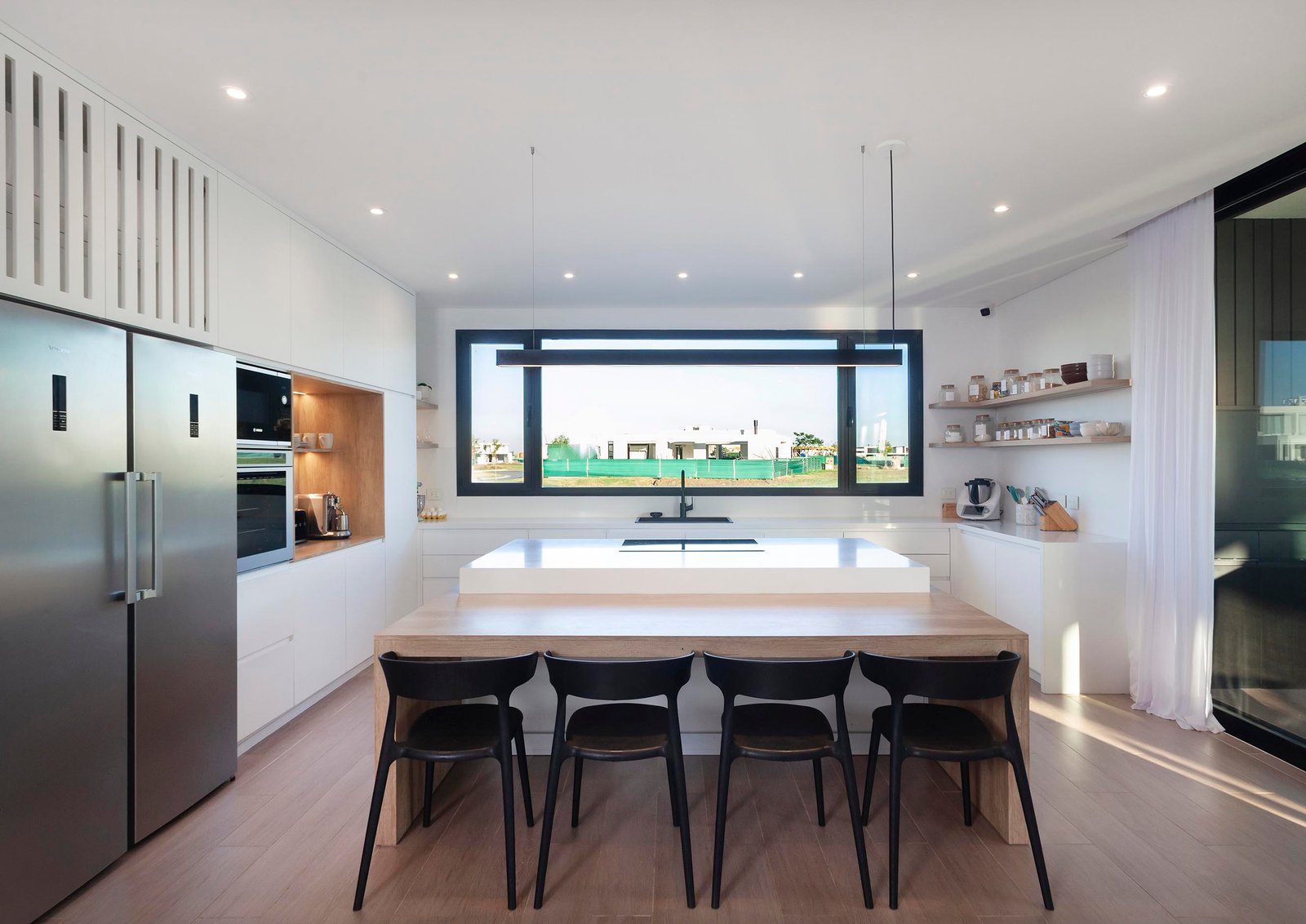 Cozinha moderna com ilha grande e parede de ripas de madeira — projeto CASA C313, por A'PRIMA - Arquitectura Sustentable, em Provincia de Buenos Aires