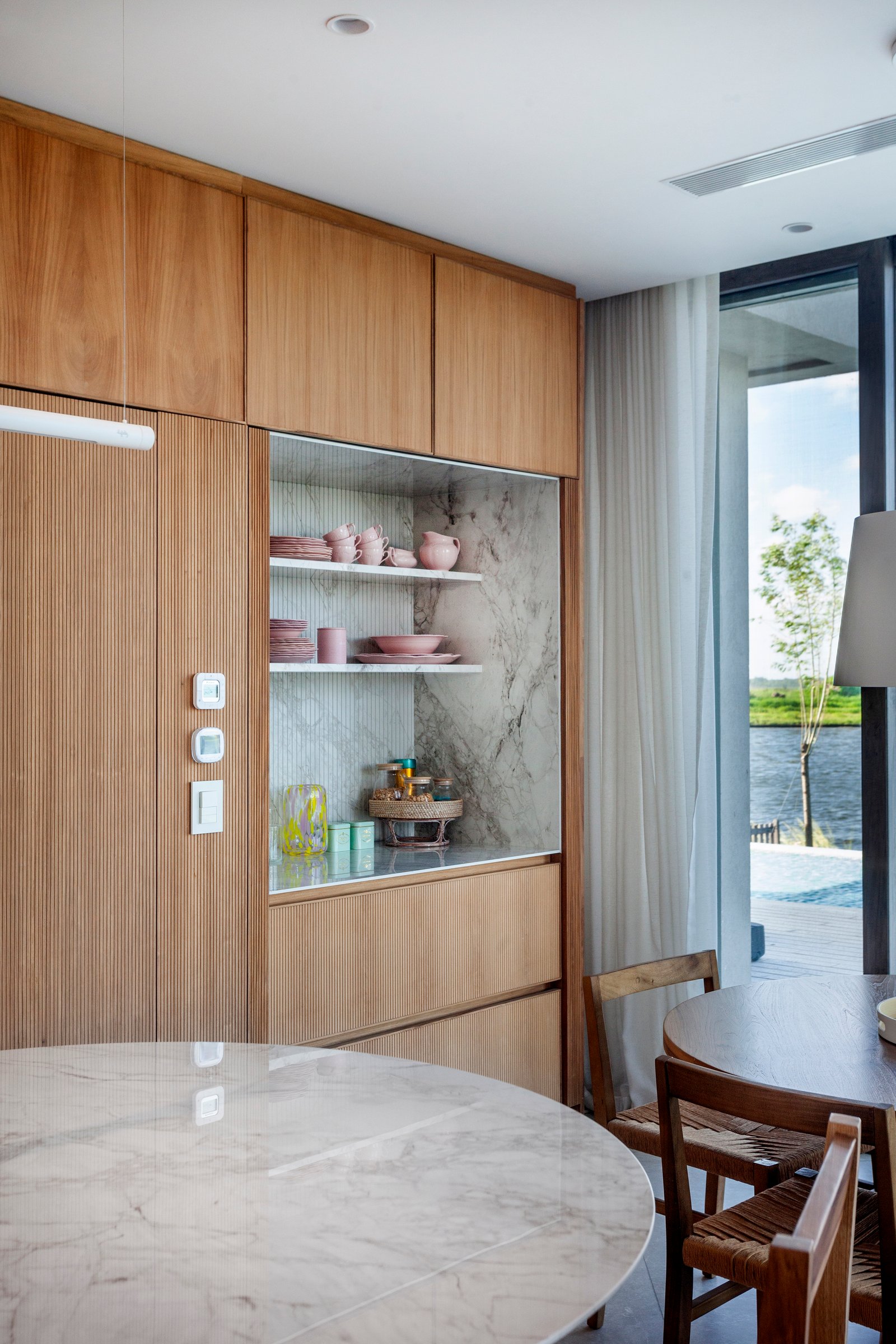 Sala de jantar moderna com vista para a costa e móveis de madeira e mármore — projeto CASA M40, por A'PRIMA - Arquitectura Sustentable, em Unnamed Road